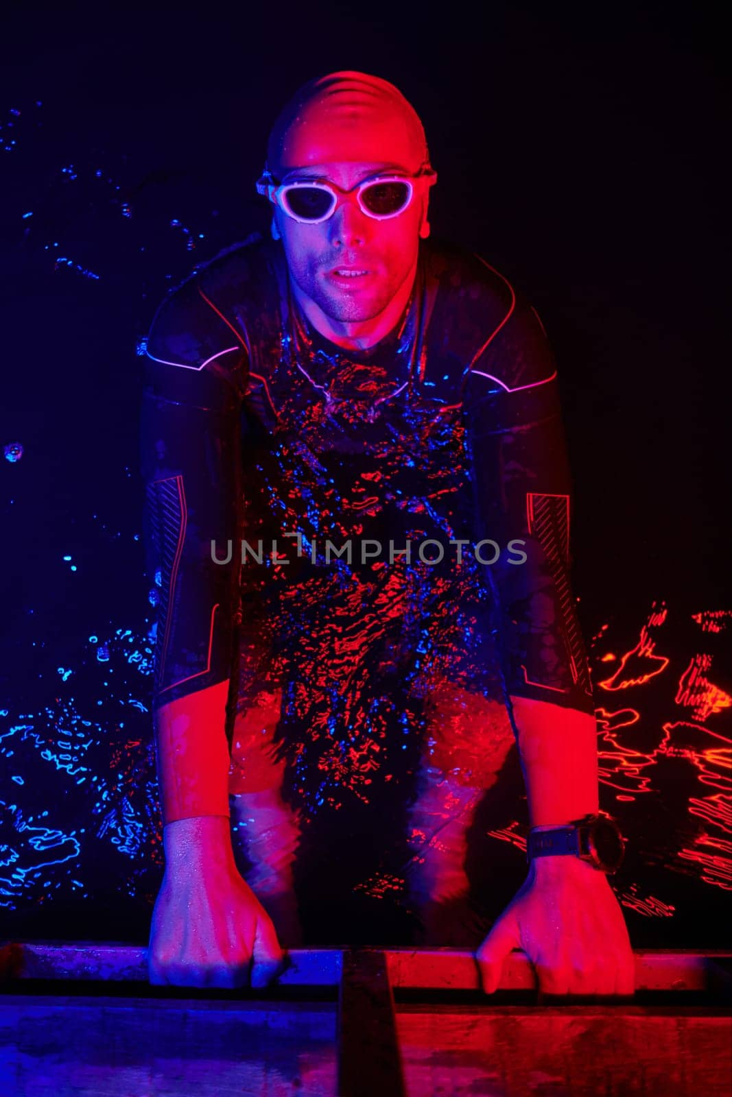 authentic triathlete swimmer having a break during hard training on night neon gel light by dotshock