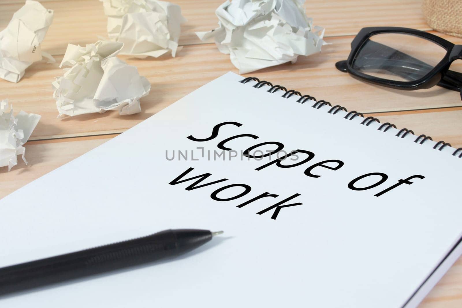 Scope of work written on notepad with trash paper background on office desk. Business concept.