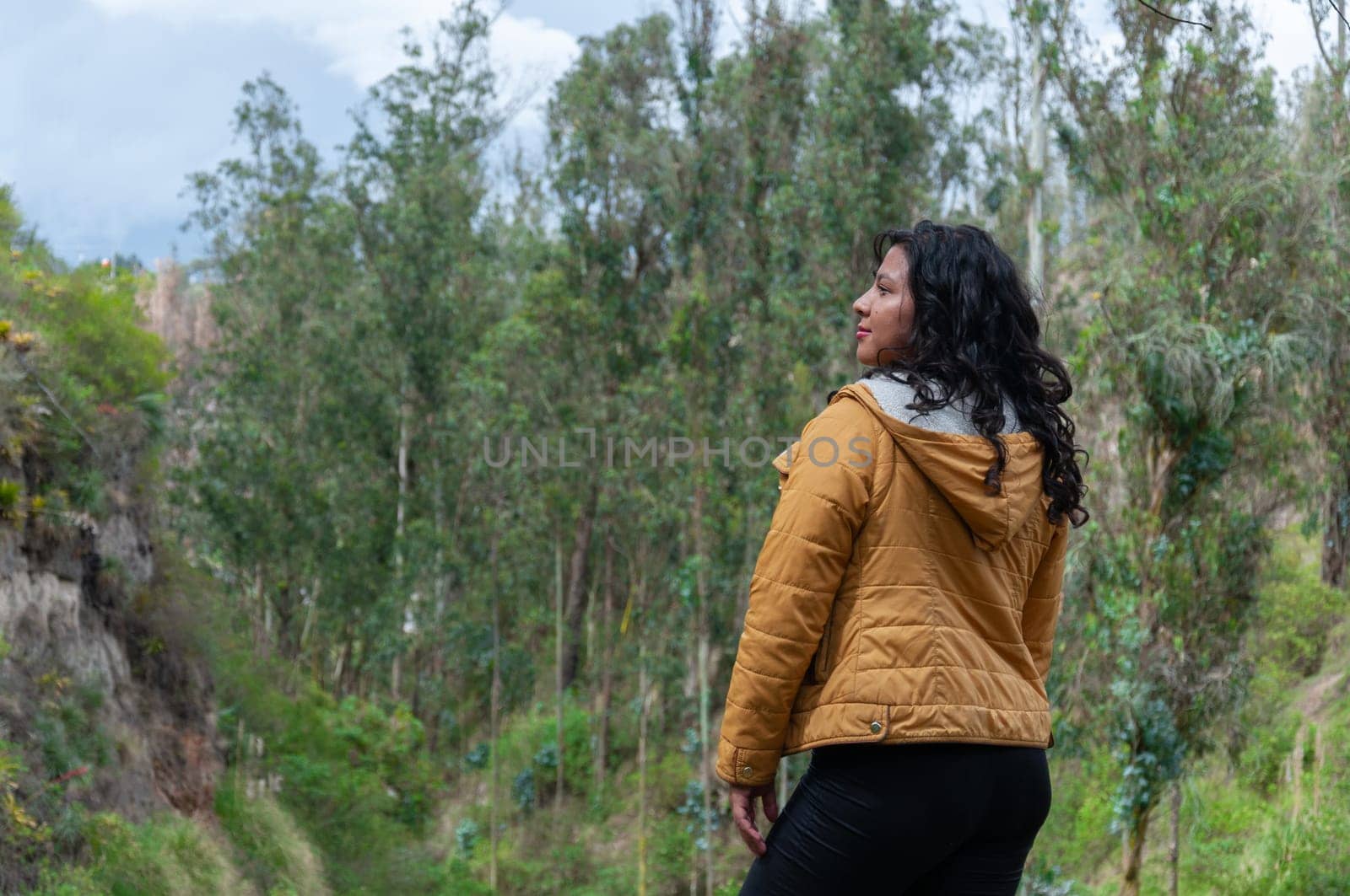 Latin girl admiring the landscape of a mountain from the top on her vacation trip to Ecuador. High quality photo