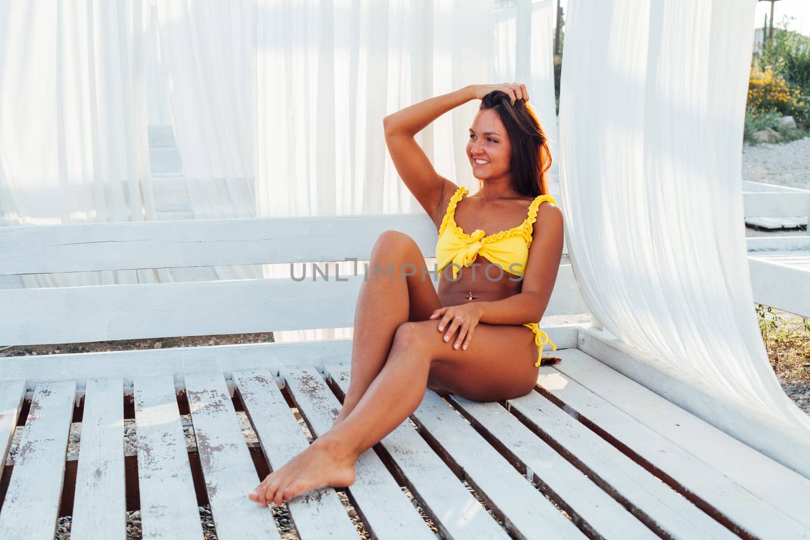 beautiful woman with long hair in yellow swimsuit on the beach by the sea