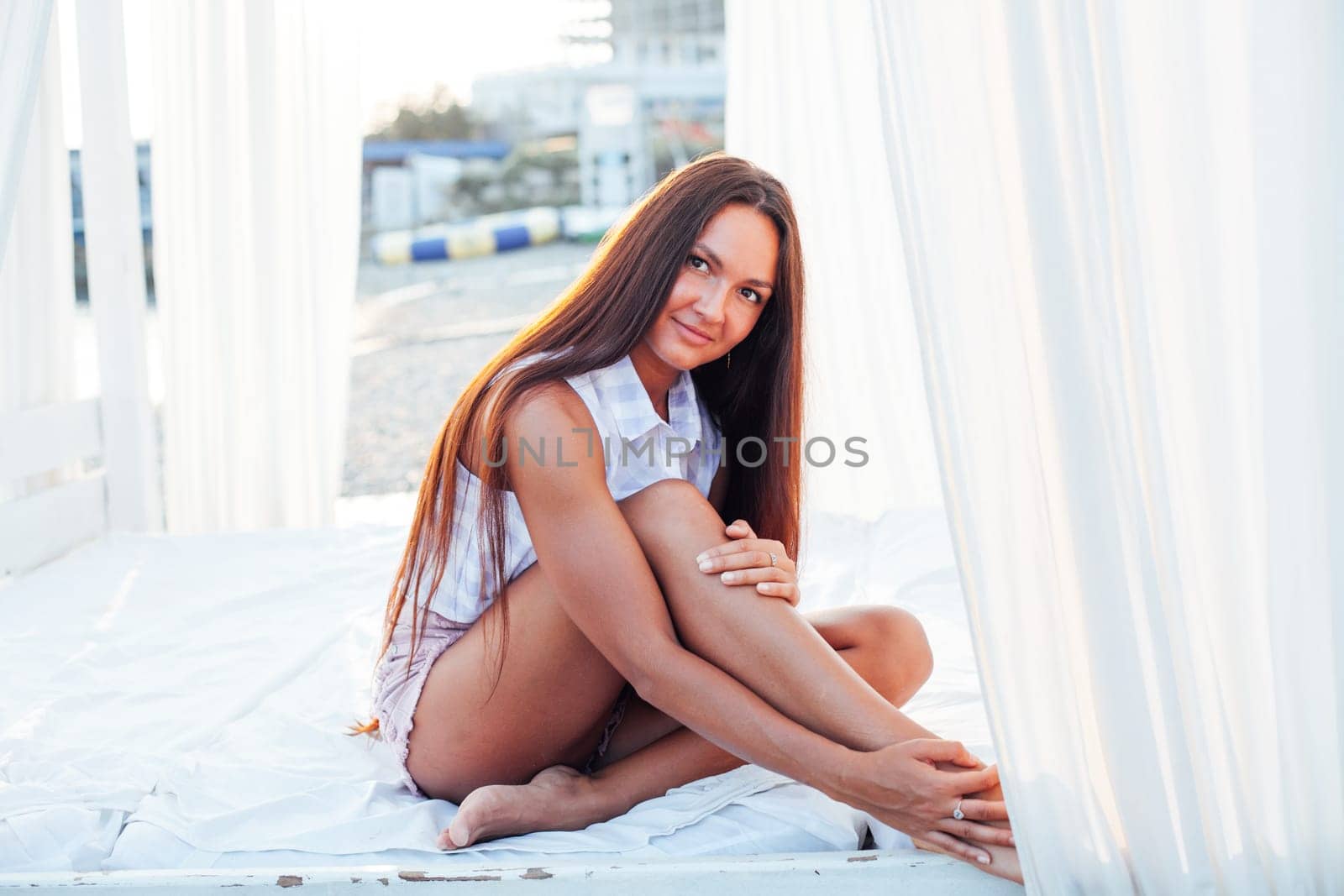 Beautiful tanned woman with long hair walks on the beach by the sea by Simakov