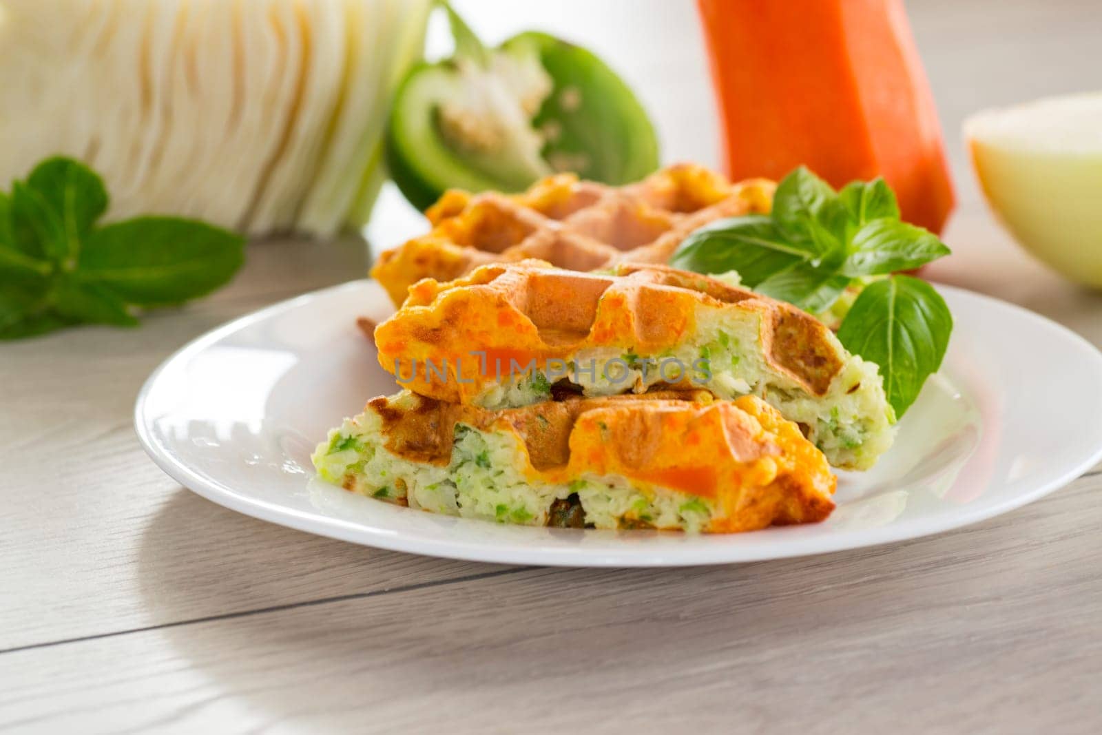 cooked two-color vegetable waffles made from cabbage and carrots, in a plate on a wooden table.
