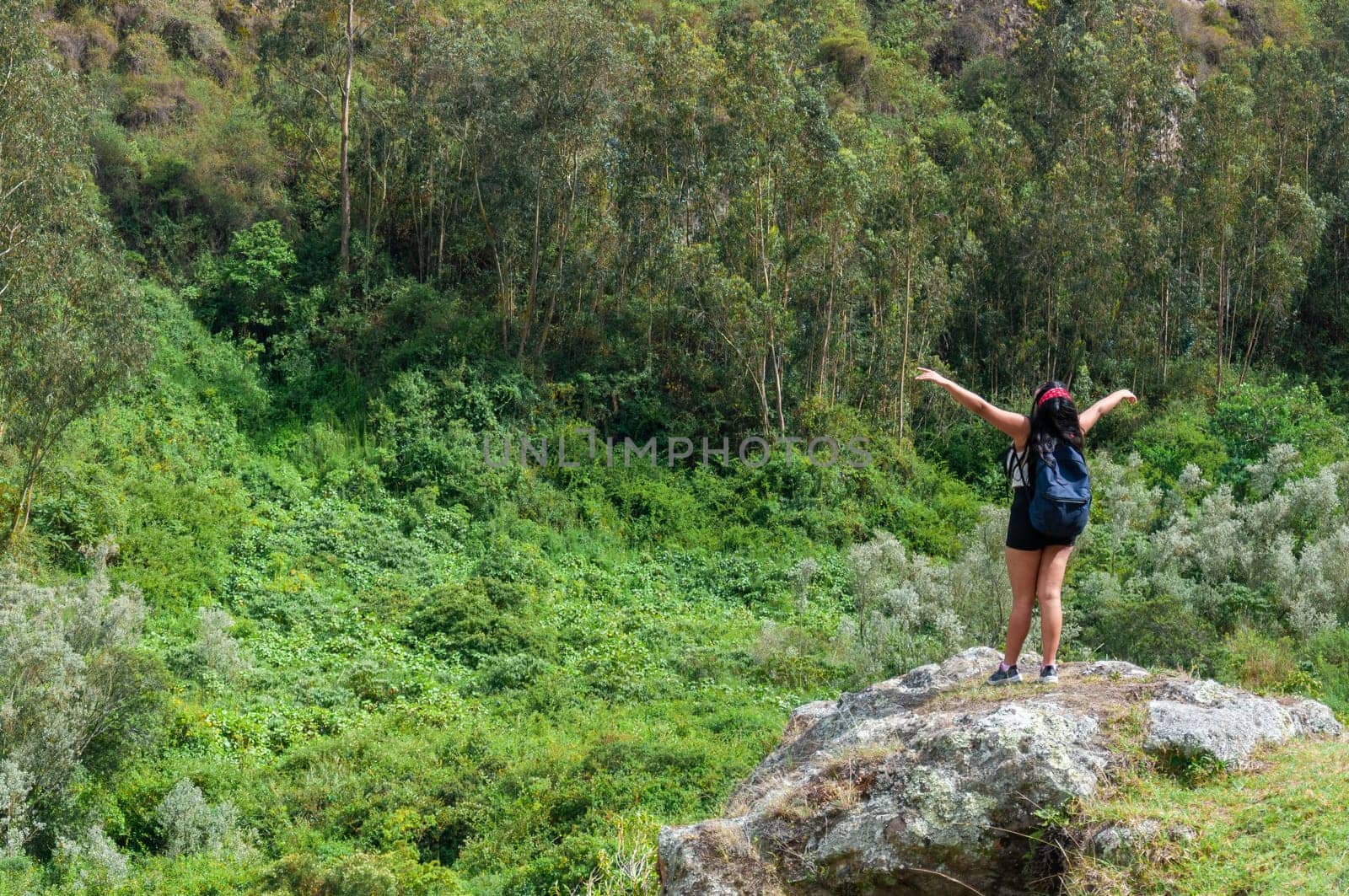 young girl from colombia on the top of a mountain feeling the freedom of a mountain in ecuador with open arms and a backpack on her back. by Raulmartin