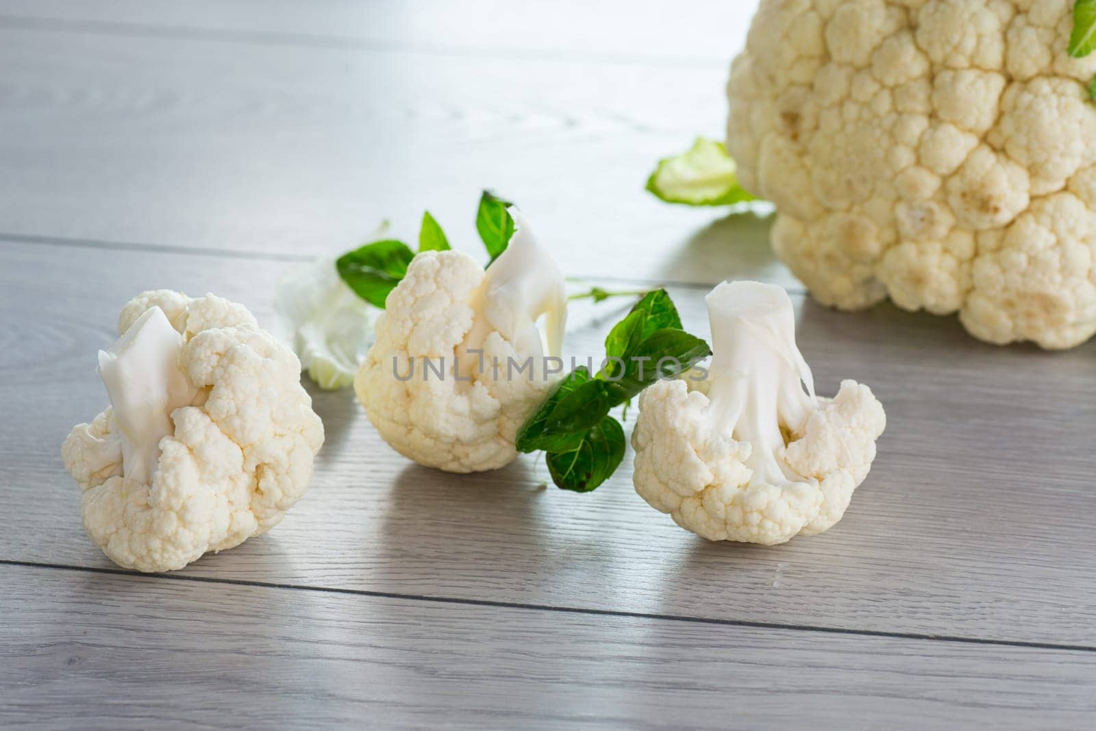 slices of raw small raw cauliflower on a light wooden table