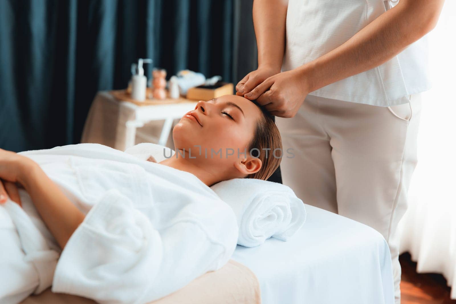 Caucasian woman enjoying relaxing anti-stress head massage and pampering facial beauty skin recreation leisure in dayspa modern light ambient at luxury resort or hotel spa salon. Quiescent