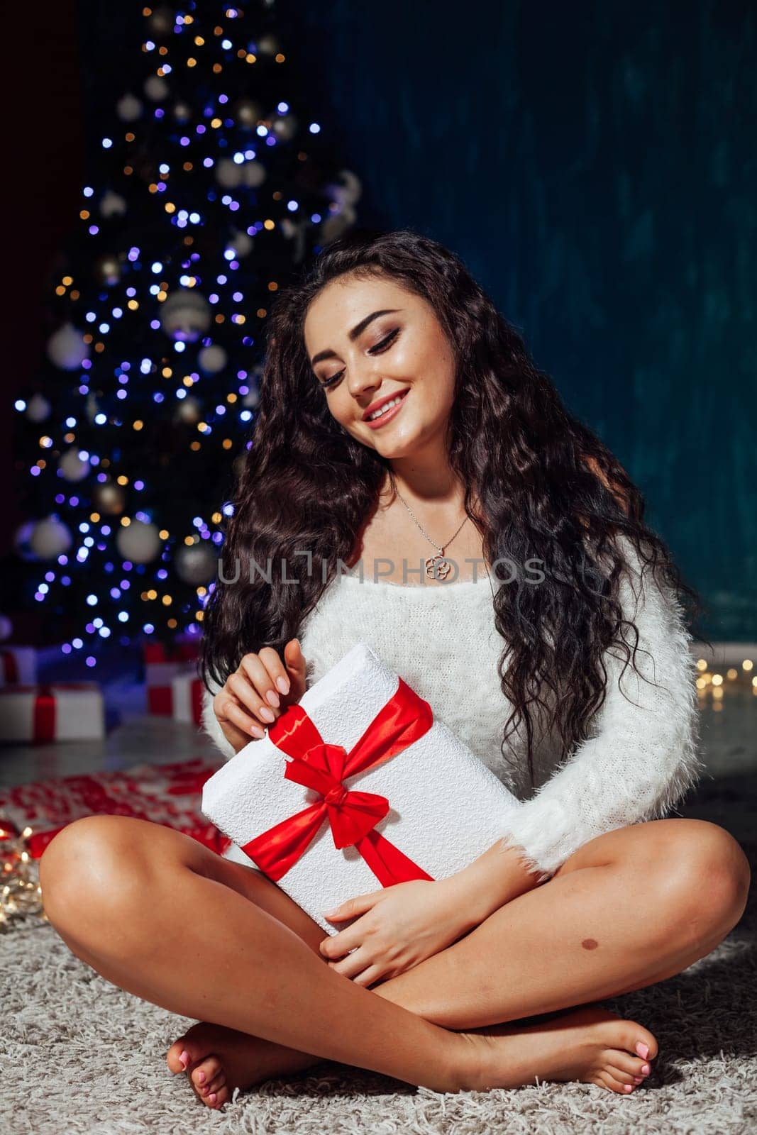 Beautiful brunette woman at christmas tree with lights garland