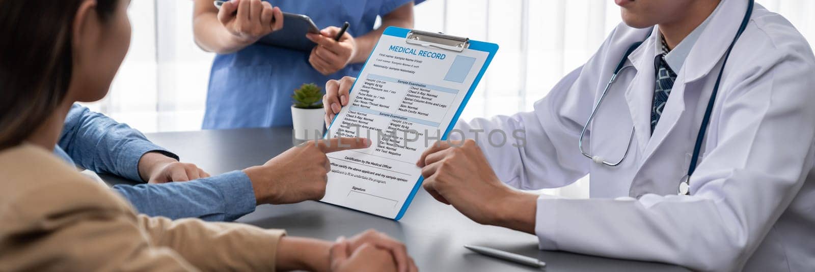 Doctor show medical diagnosis report and providing compassionate healthcare consultation to young couple patient in doctor clinic office. Doctor appointment and medical consult concept. Neoteric