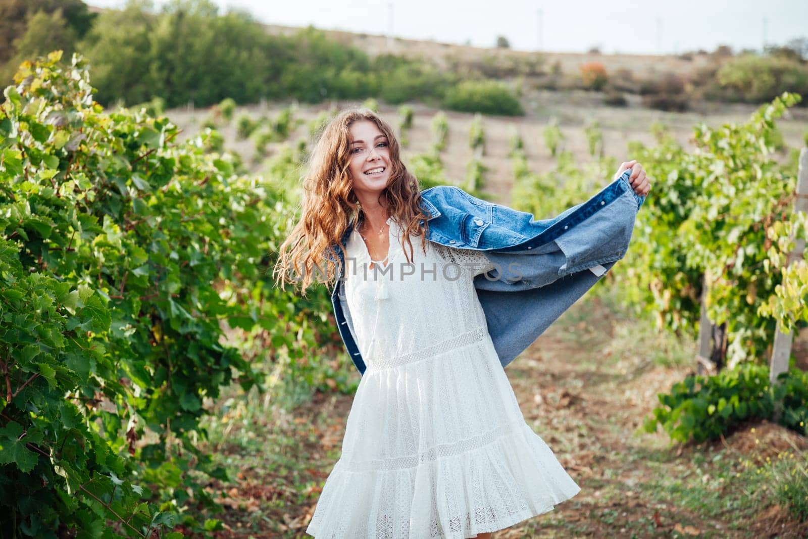 beautiful woman in white dress and denim jacket in the garden of vineyards