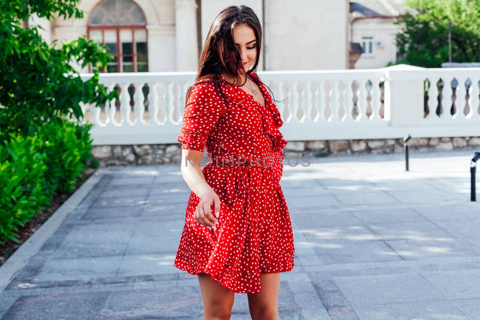 brunette woman in red polka dot dress walks the streets of the city
