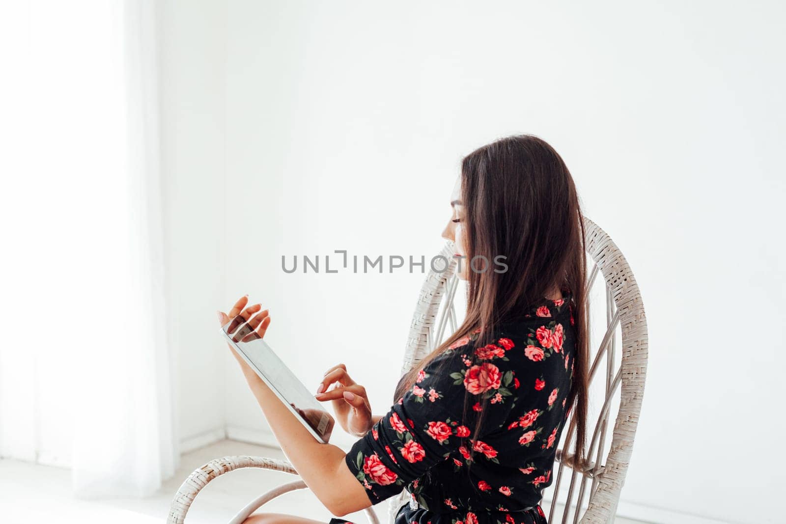 Beautiful fashionable woman in a chair with an internet tablet by Simakov