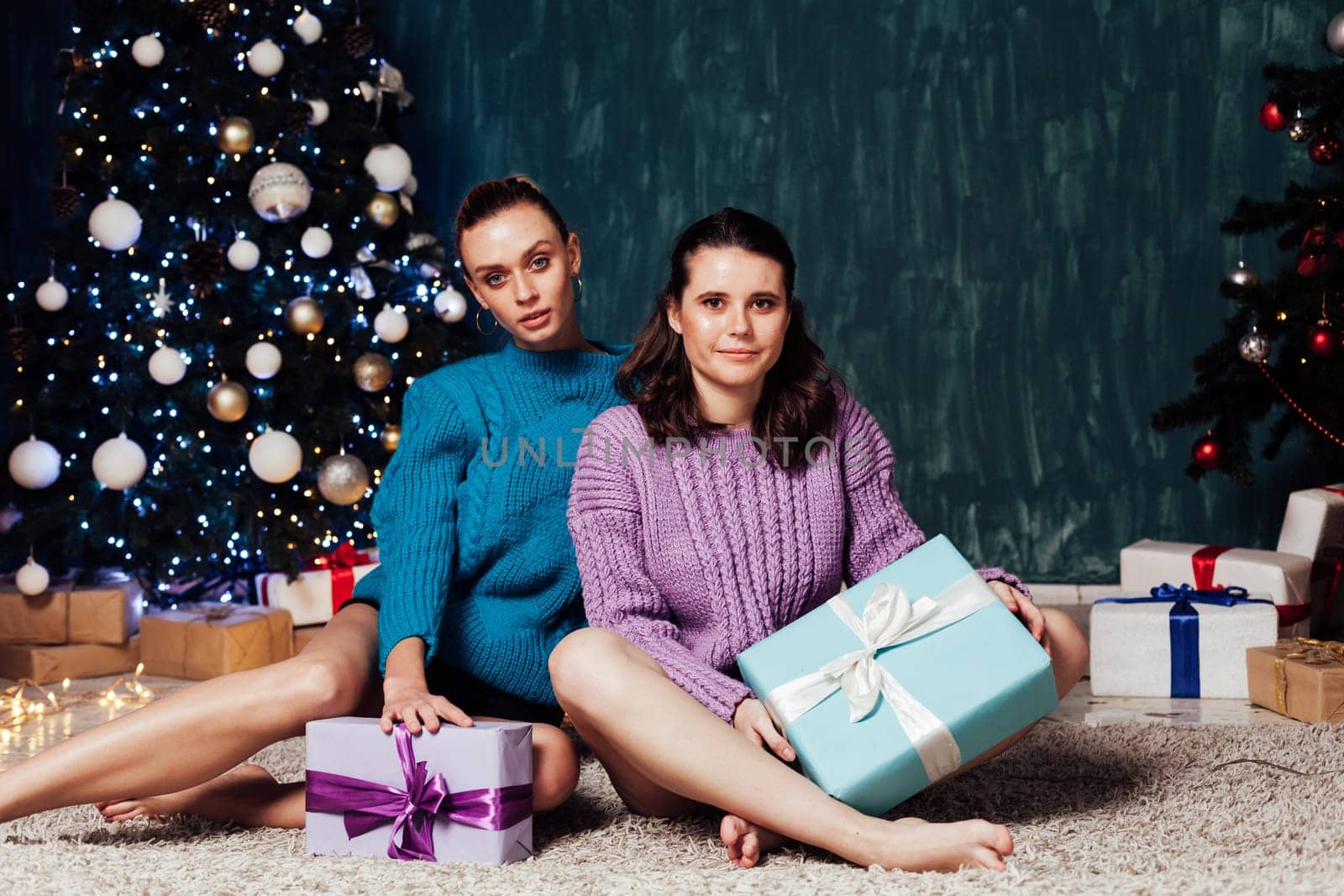 Two women with gifts at the Christmas tree for the new year