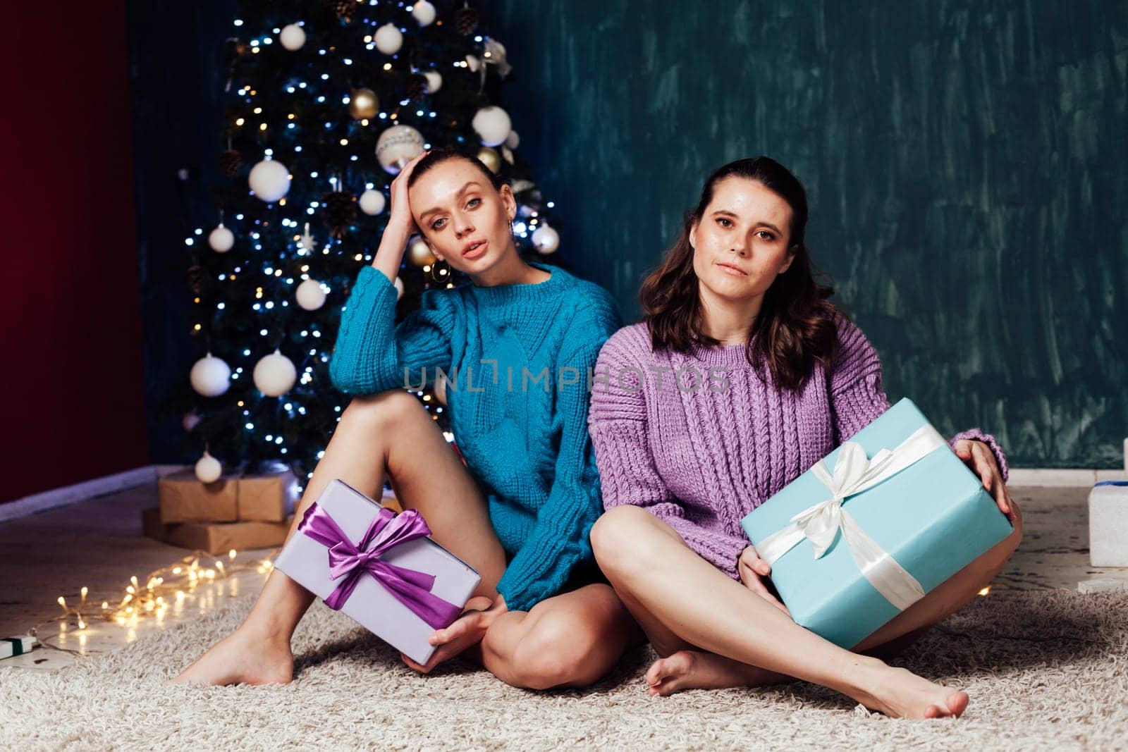 Two women with gifts at the Christmas tree for the new year