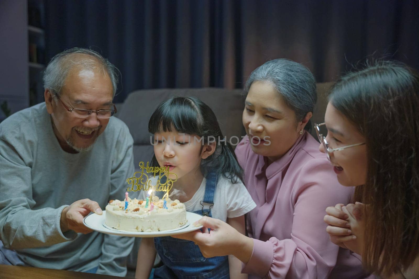 Happy Asian family grandparents and mother celebrating enjoy birthday party by Sorapop
