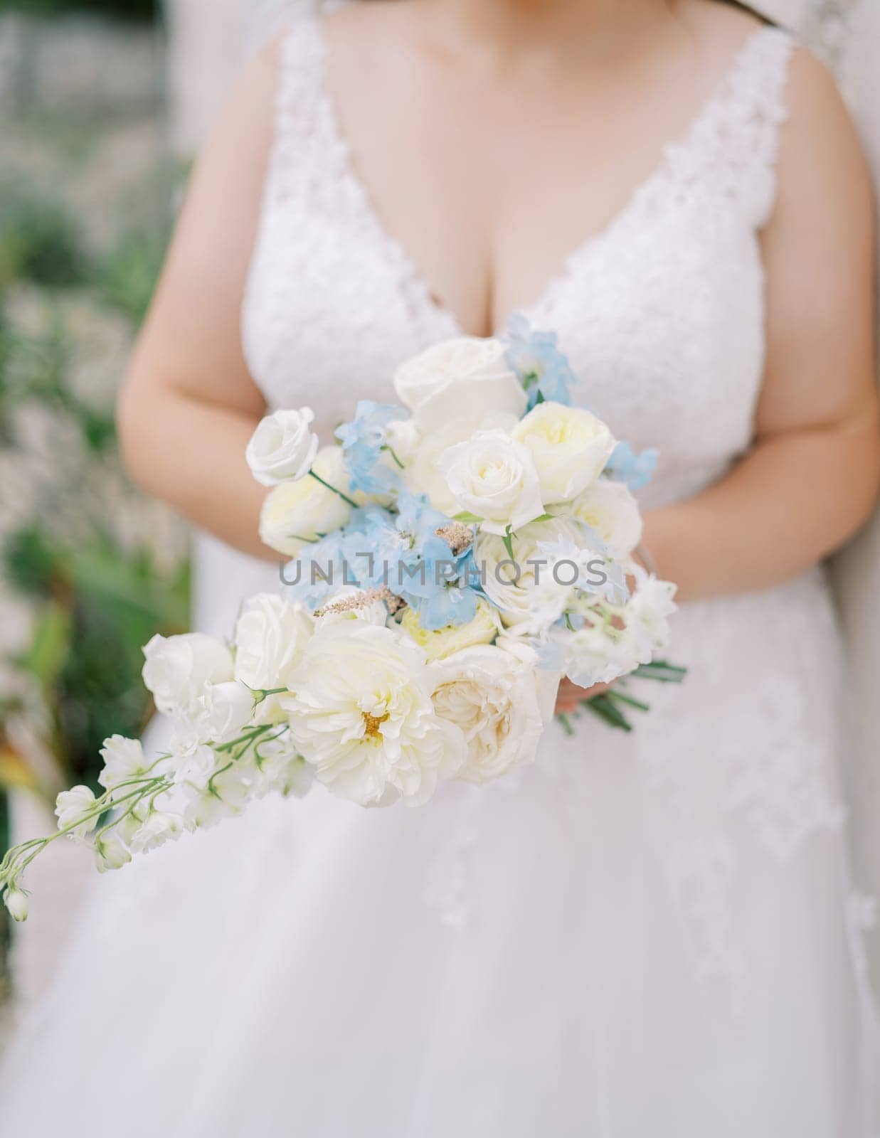Bouquet of flowers in the hands of a bride in a lace dress. Cropped. Faceless by Nadtochiy