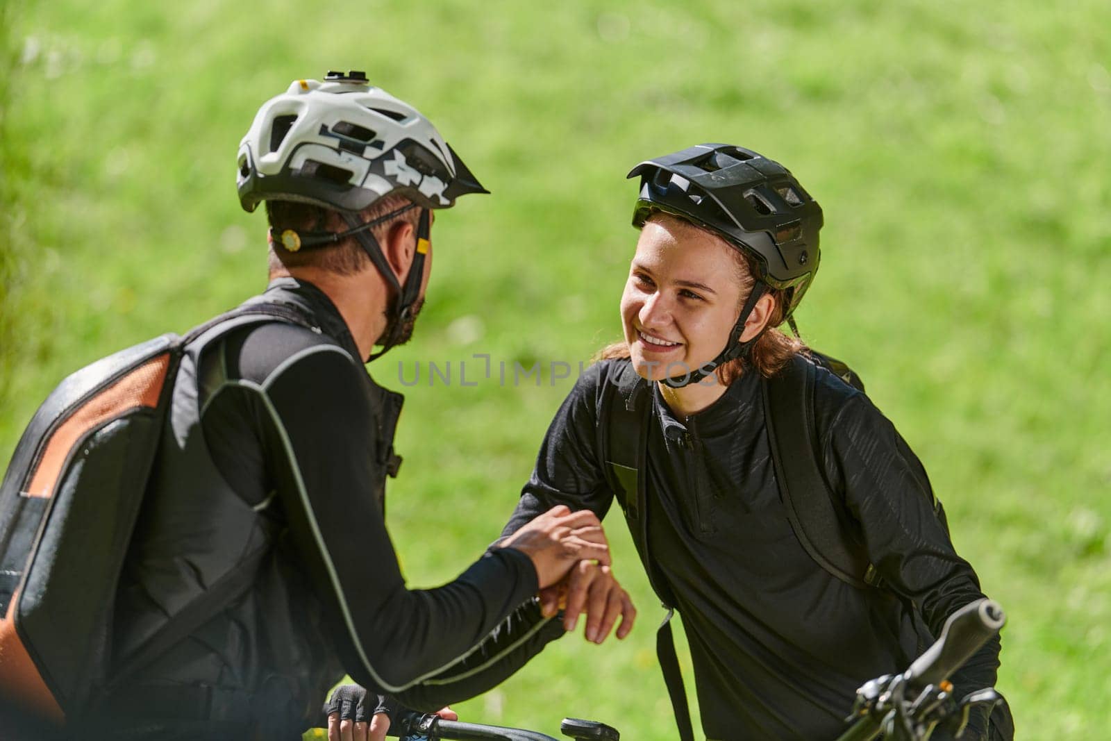 A sweet couple, equipped with bicycles and engrossed in coordinating their journey, checks their GPS mobile and watches while planning scenic routes in the park, seamlessly blending technology and outdoor adventure for a delightful cycling experience by dotshock