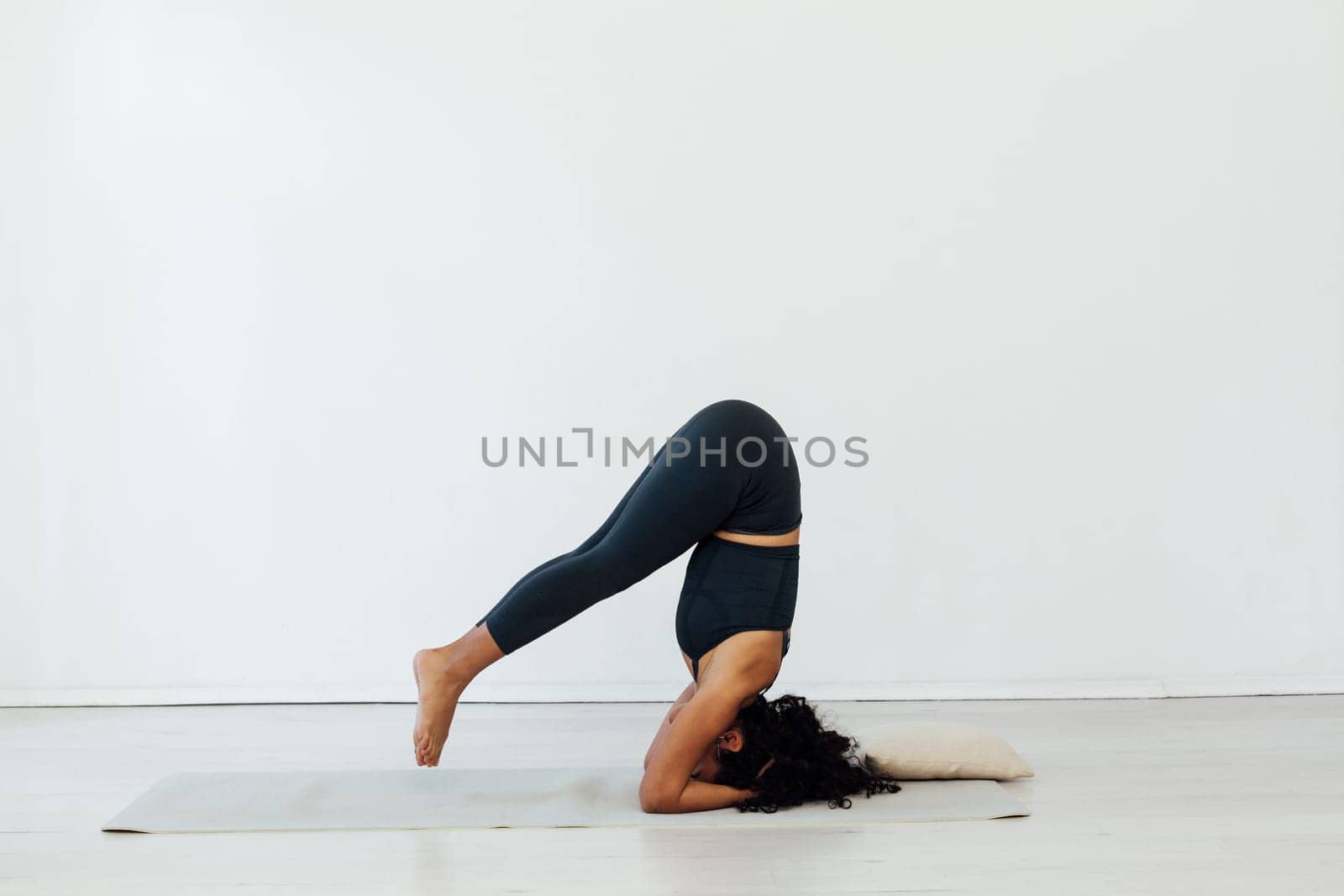 Beautiful brunette woman engaged in yoga asana gymnastics fitness stands on her head