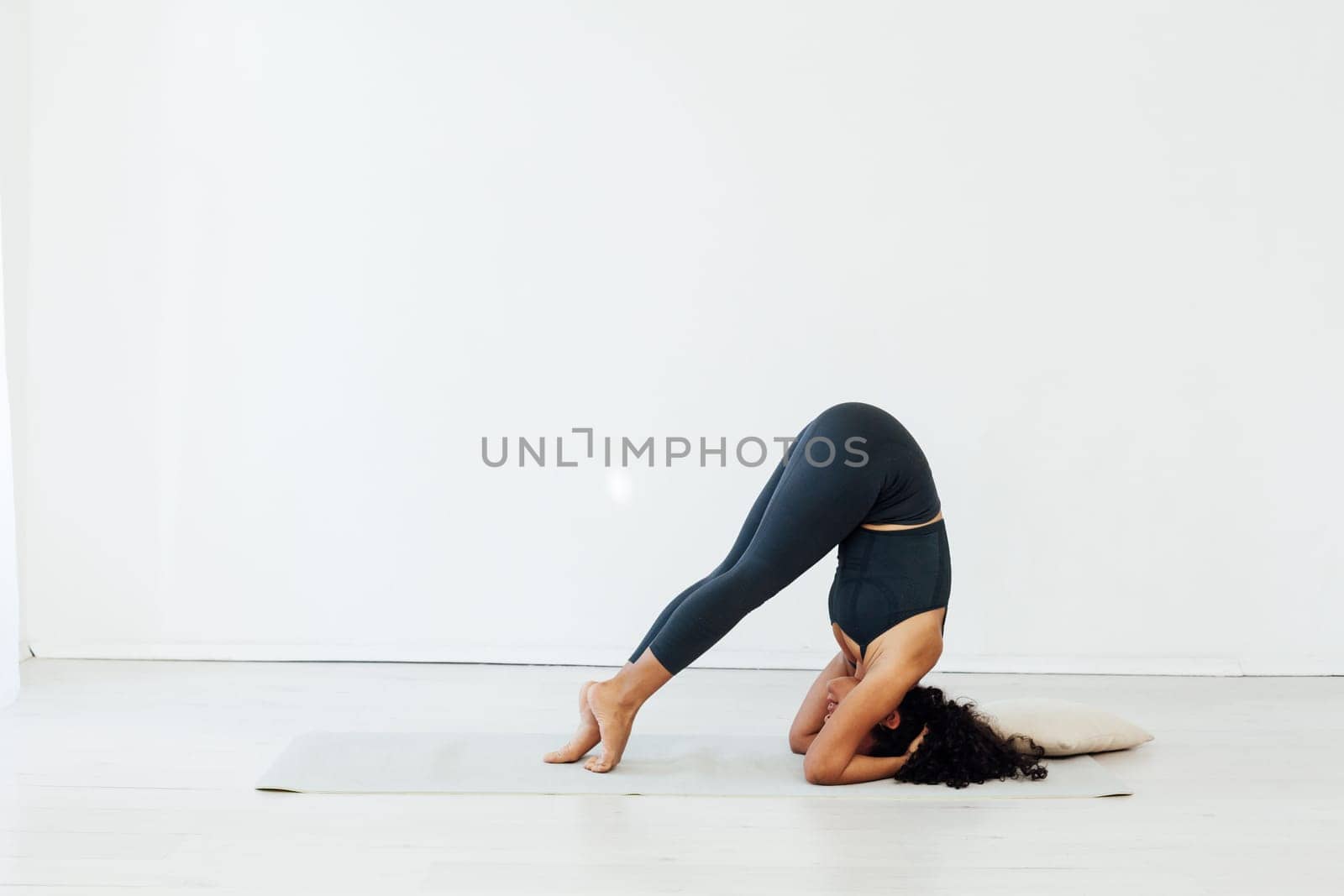 Beautiful brunette woman engaged in yoga asana gymnastics fitness stands on her head