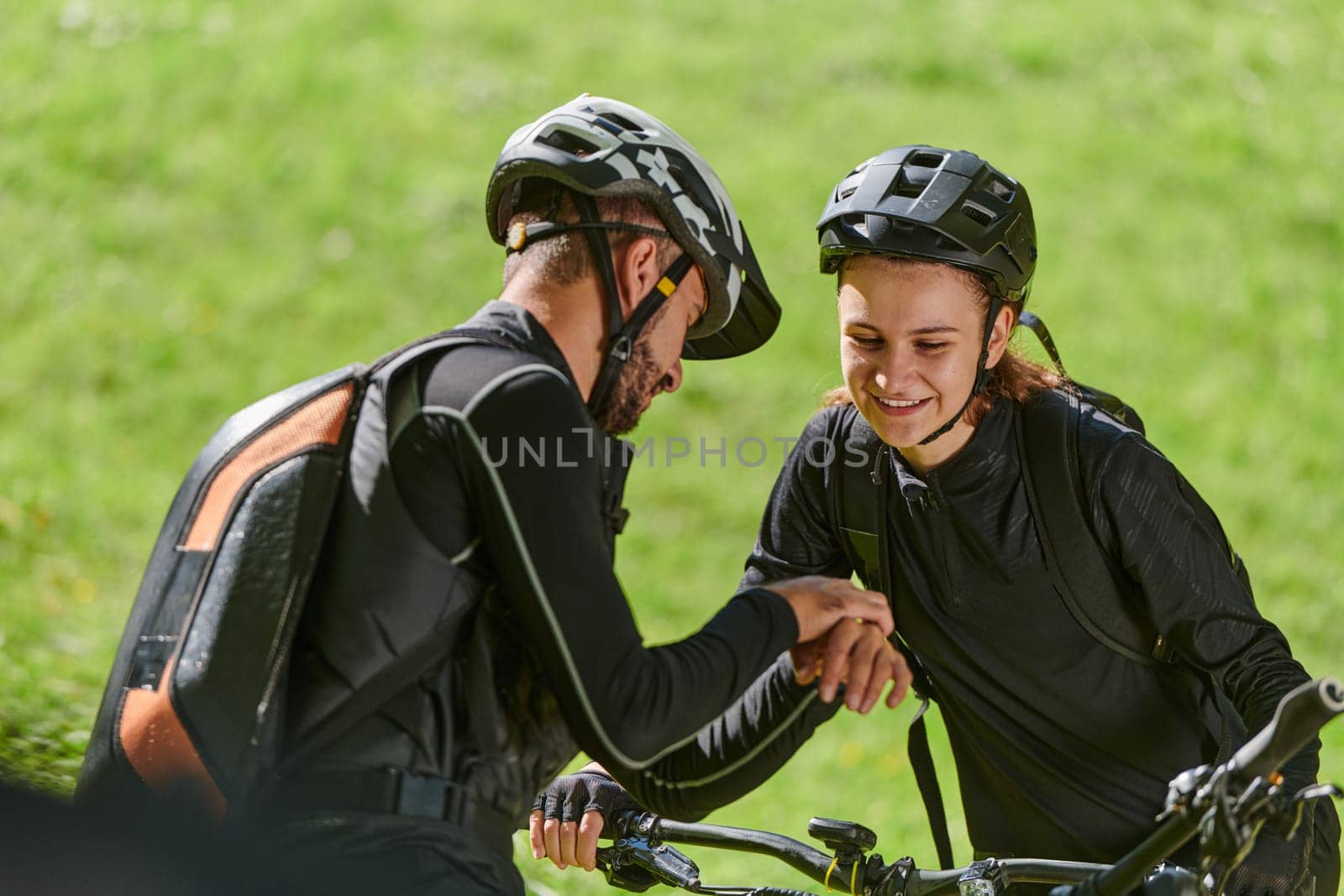 A sweet couple, equipped with bicycles and engrossed in coordinating their journey, checks their GPS mobile and watches while planning scenic routes in the park, seamlessly blending technology and outdoor adventure for a delightful cycling experience.
