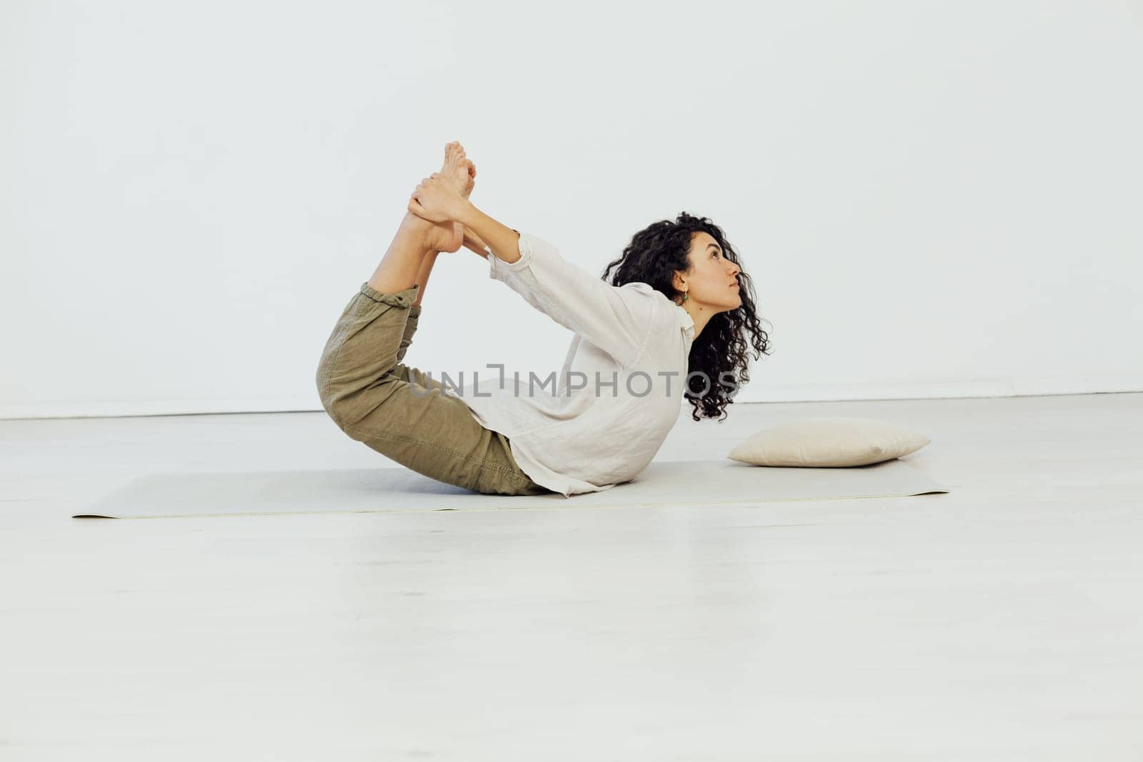 Brunette woman engaged in yoga asana gymnastics flexibility body by Simakov