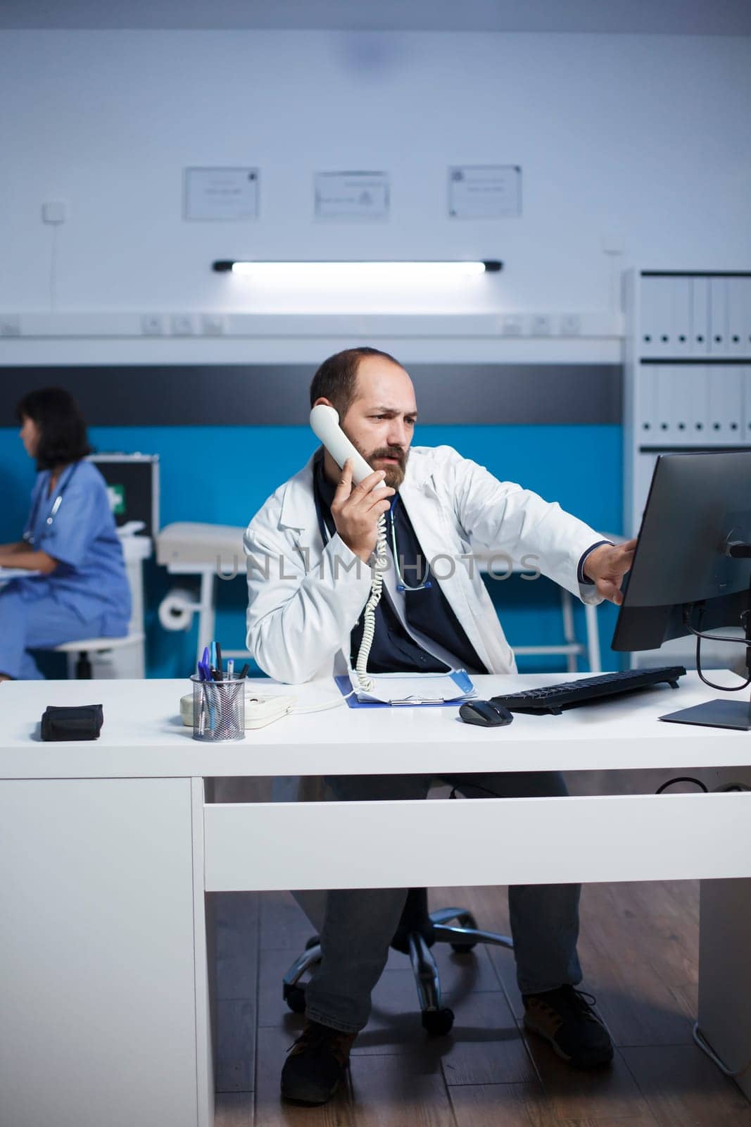 Physician using a landline phone by DCStudio