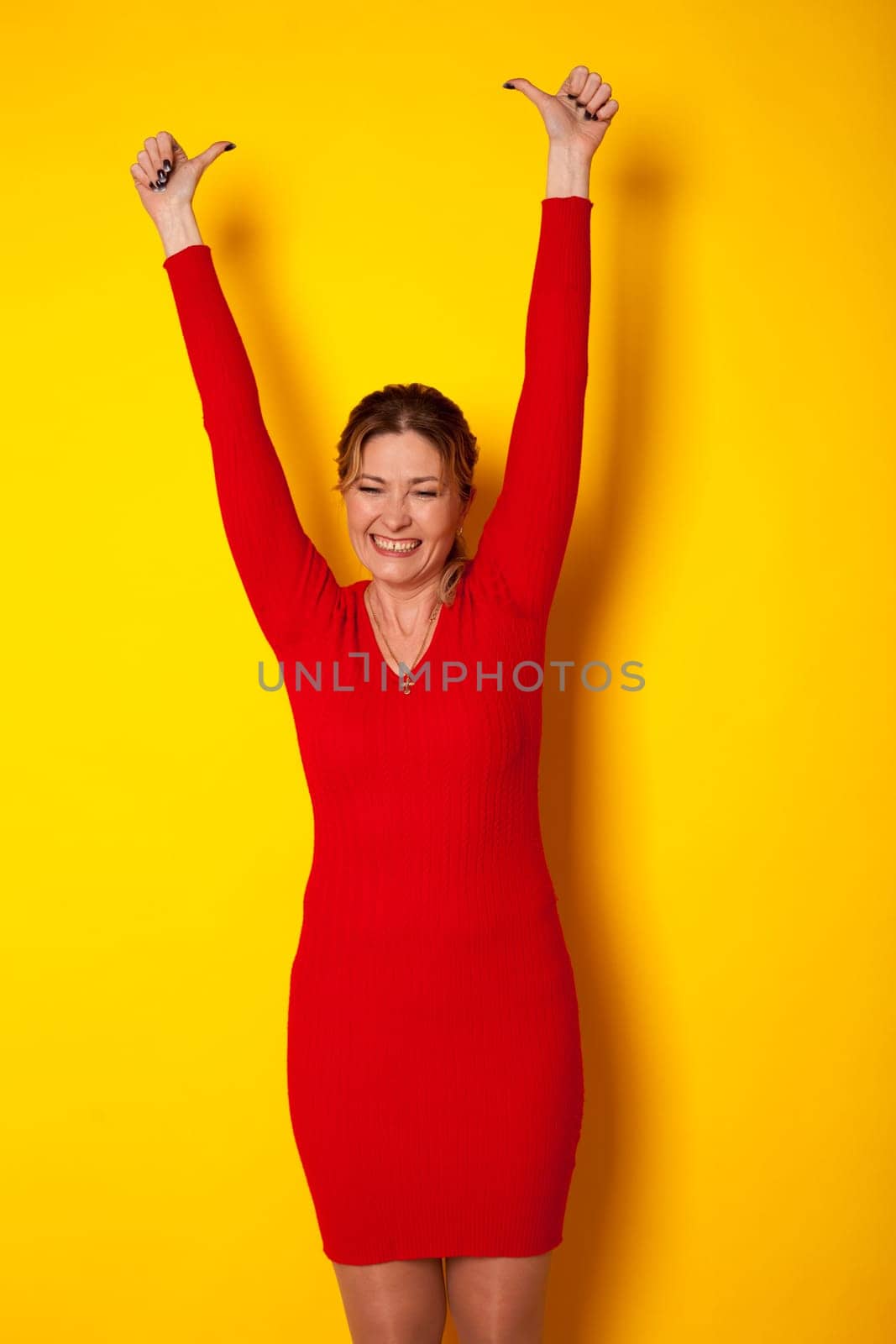 woman in dress yellow background hands up
