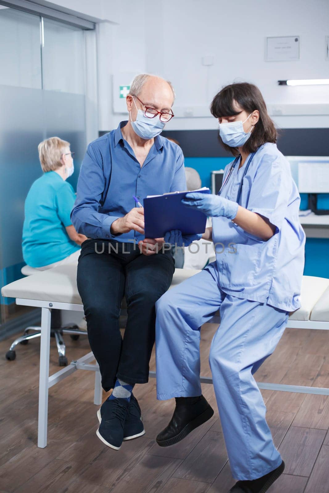 Nurse and old man looking at paperwork by DCStudio