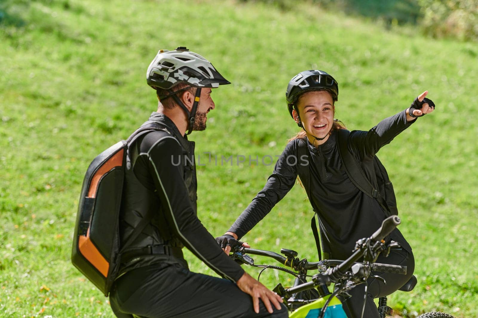 A sweet couple, equipped with bicycles and engrossed in coordinating their journey, checks their GPS mobile and watches while planning scenic routes in the park, seamlessly blending technology and outdoor adventure for a delightful cycling experience by dotshock