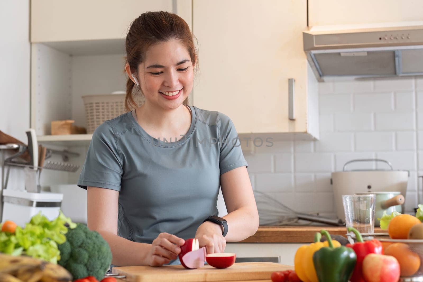 Healthy Asian woman takes care of her health by eating vegetable and fruit salad, adding vitamins in the kitchen..