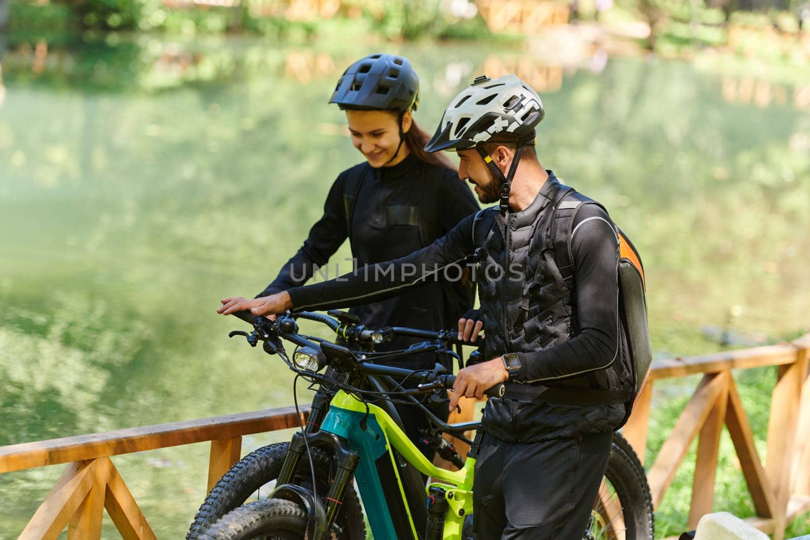 A blissful couple, adorned in professional cycling gear, enjoys a romantic bicycle ride through a park, surrounded by modern natural attractions, radiating love and happiness.