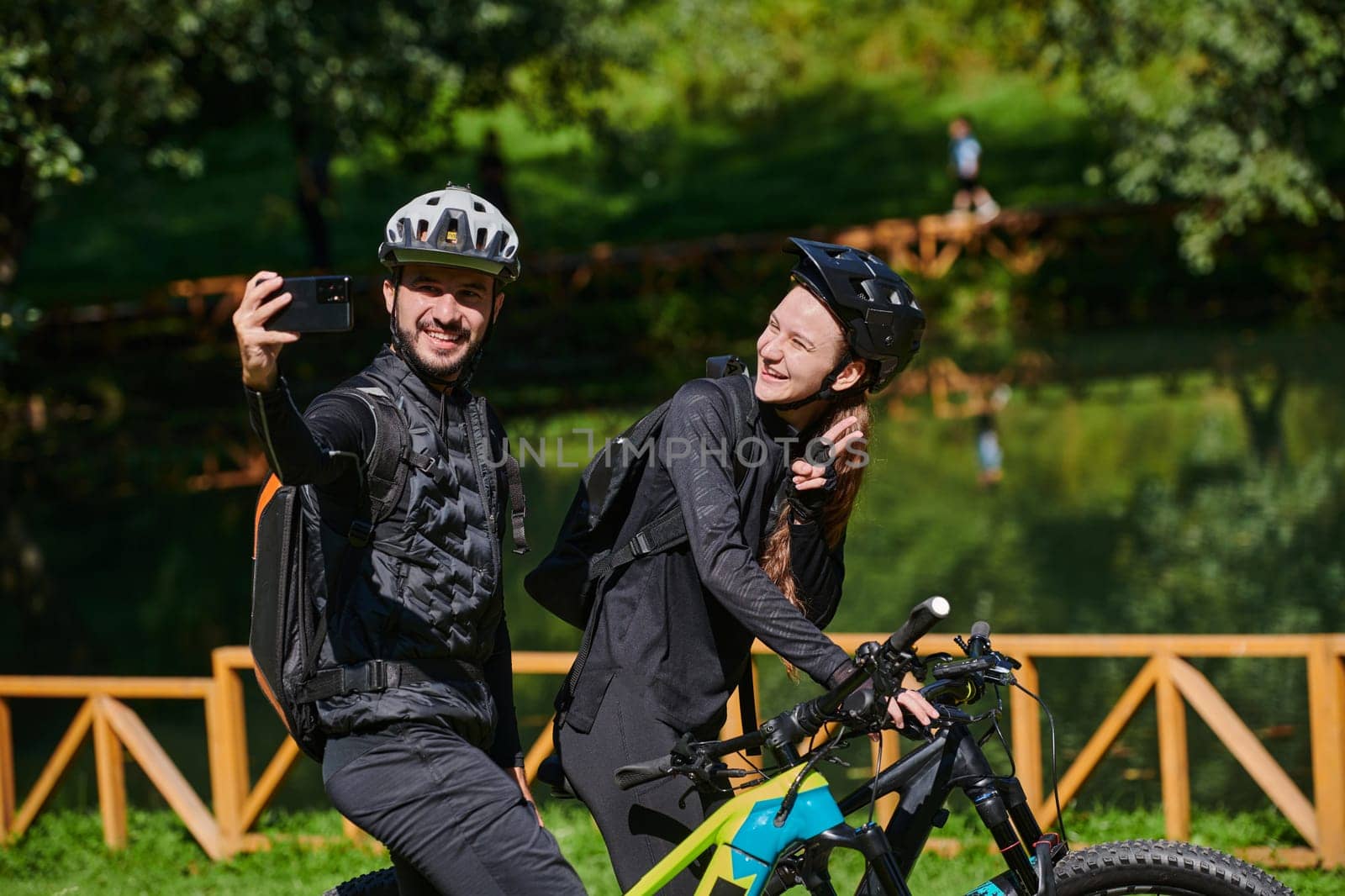 A modern couple captures the joy of their bike ride in the park through a trendy selfie, blending technology and outdoor adventure to immortalize a moment of happiness and togetherness.