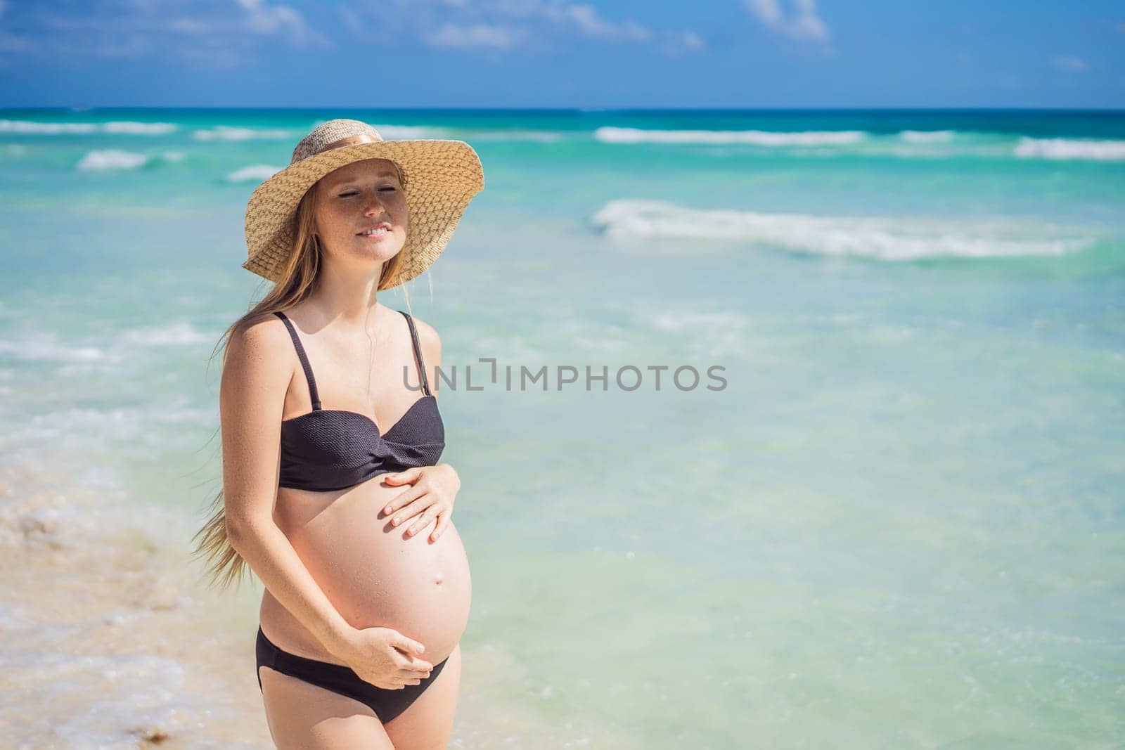 Radiant and expecting, a pregnant woman stands on a pristine snow-white tropical beach, celebrating the miracle of life against a backdrop of natural beauty by galitskaya