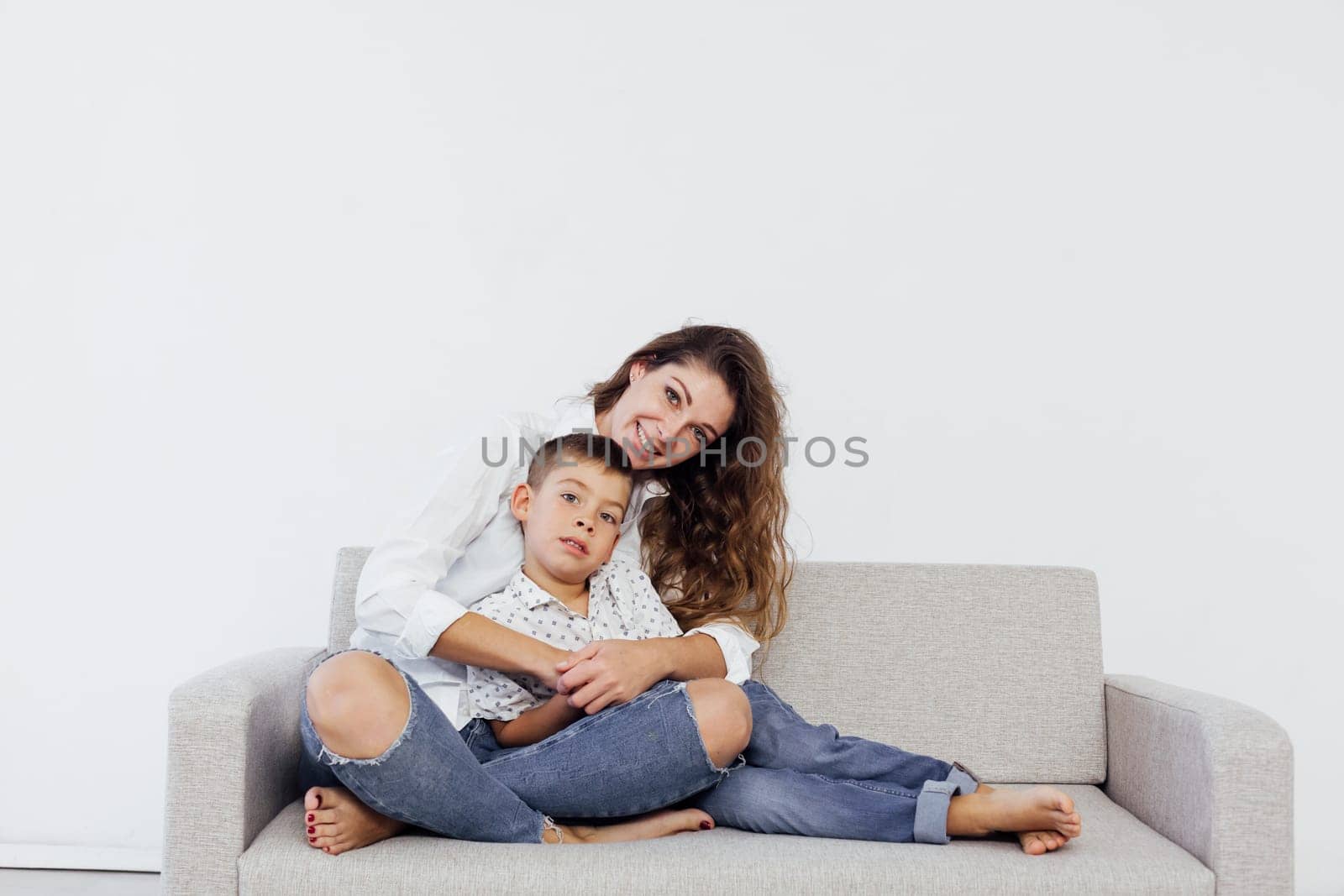 Mom and son sit on the sofa at home in a room