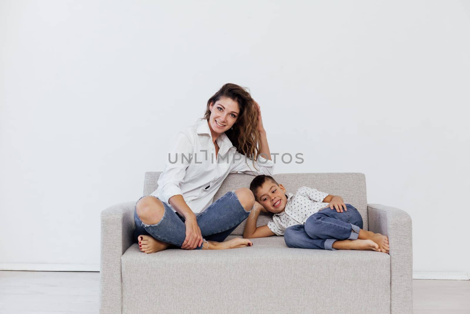 Mom and son sit on the sofa at home in a room