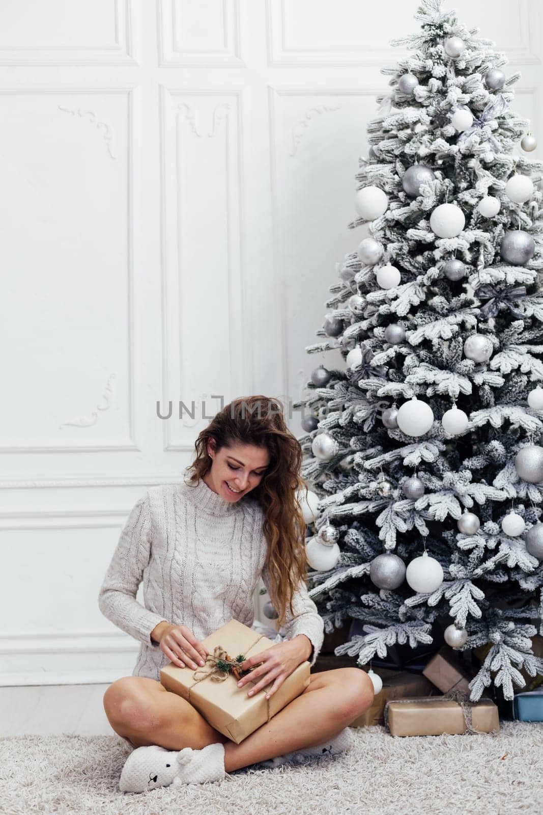 woman opens a gift at the Christmas tree with gifts new year