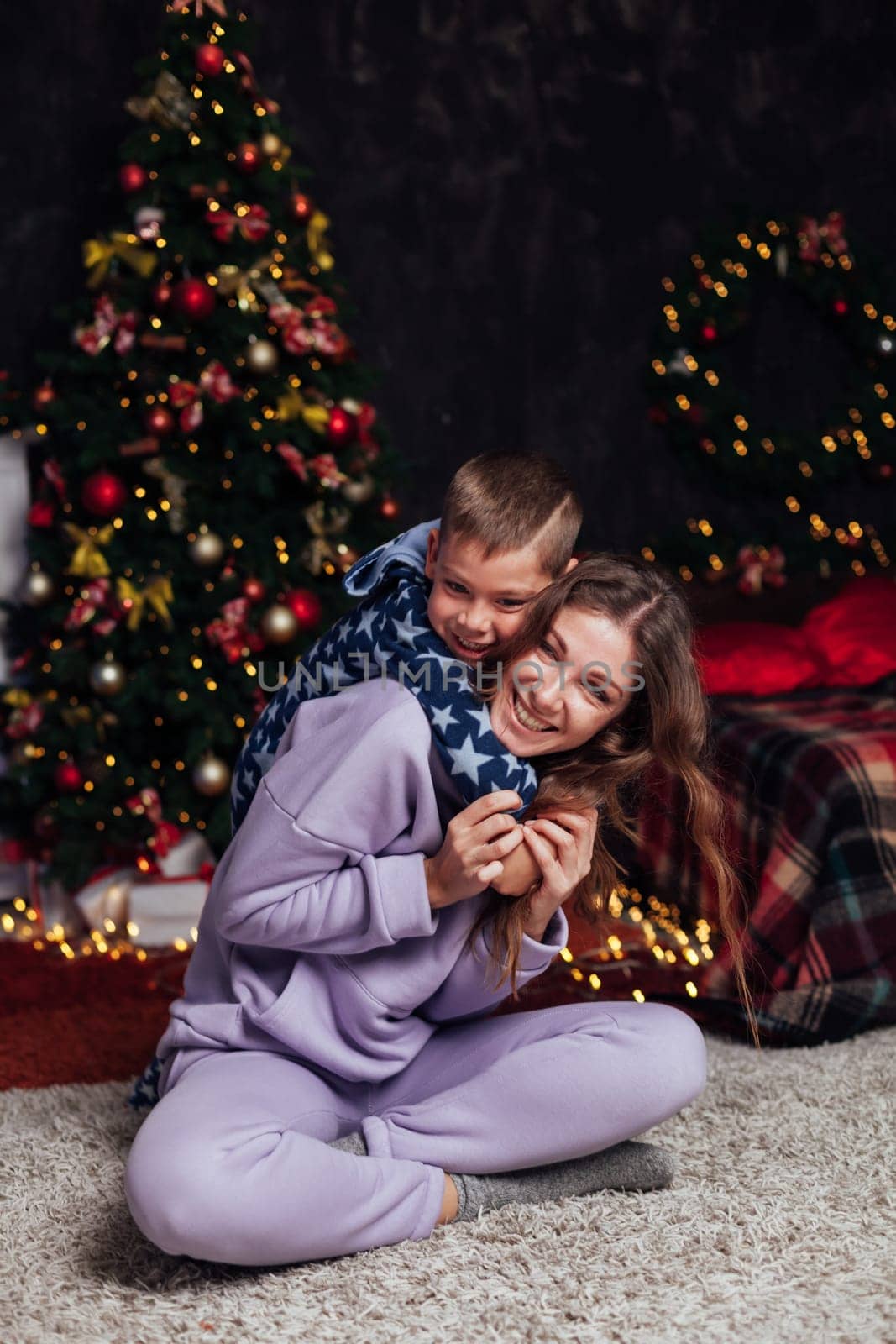 woman with son decorates white Christmas tree with new year gifts