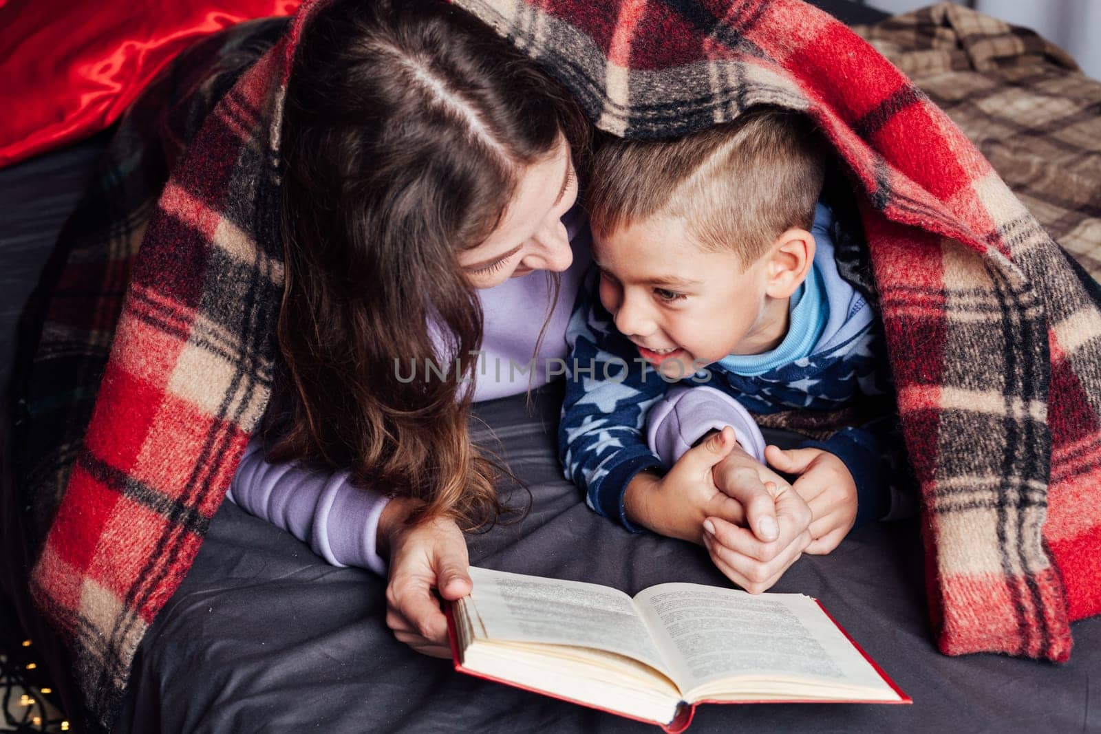 mother reads her son a book in bed before going to bed new year