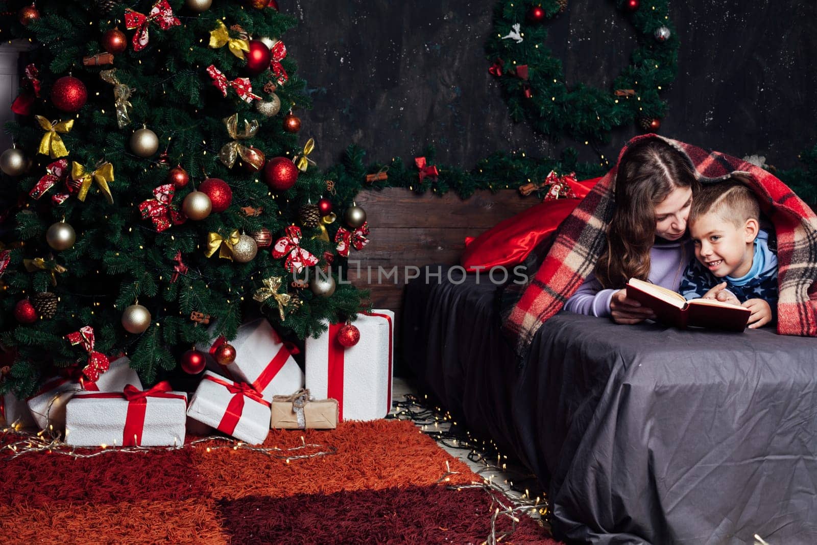 mother reads her son a book in bed before going to bed new year