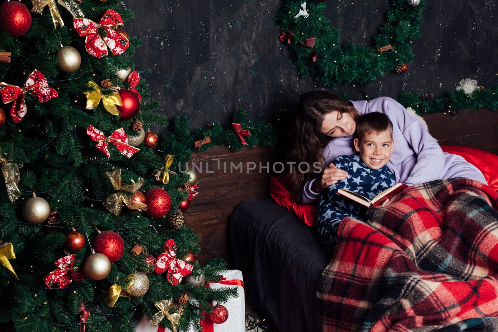 mother reads her son a book in bed before going to bed new year