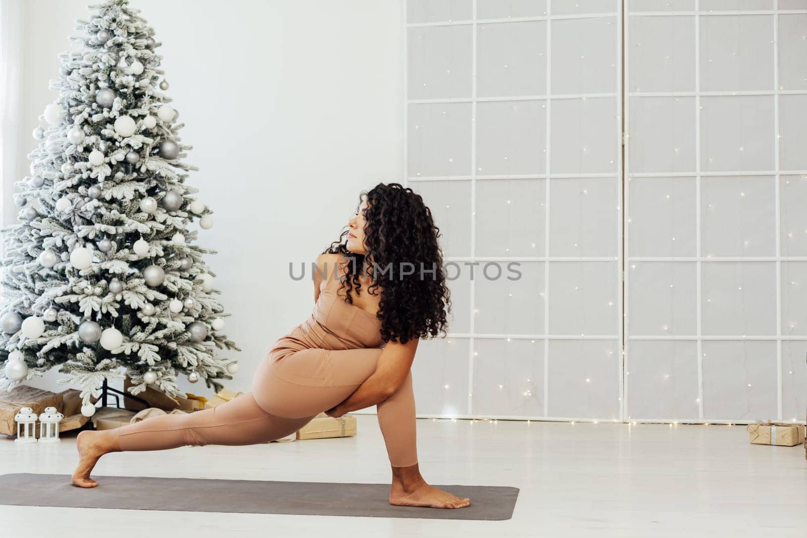 Woman yoga asana at Christmas tree New Year