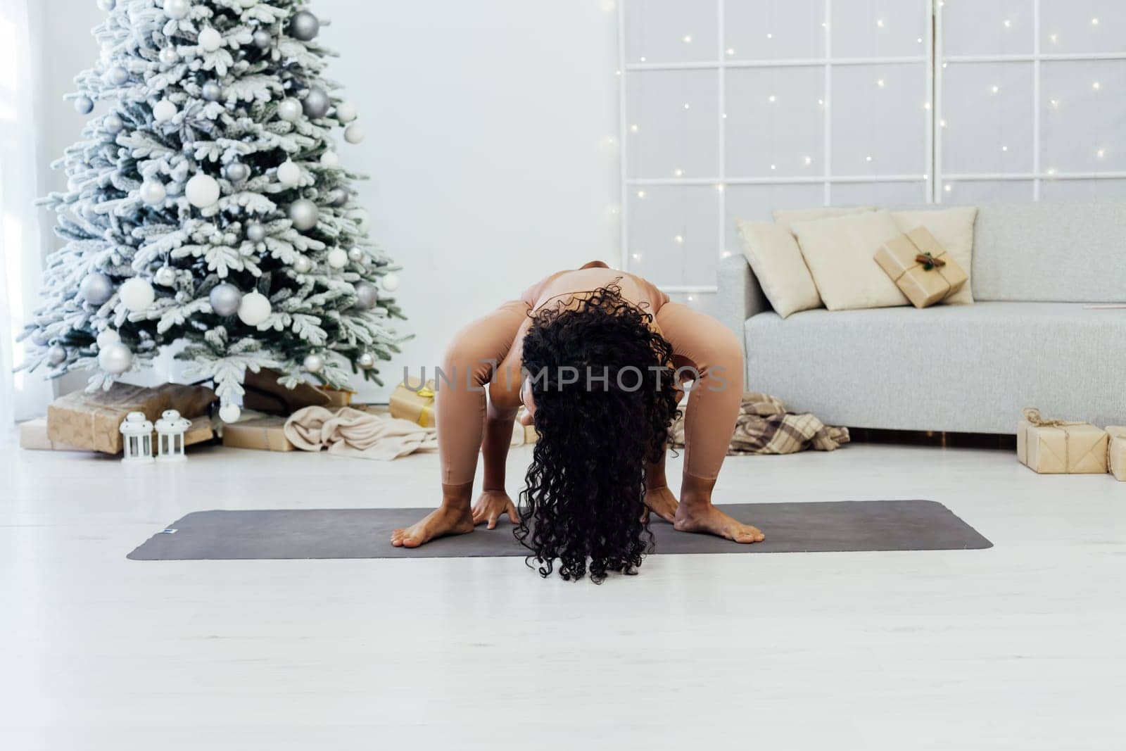 Woman yoga asana at Christmas tree New Year