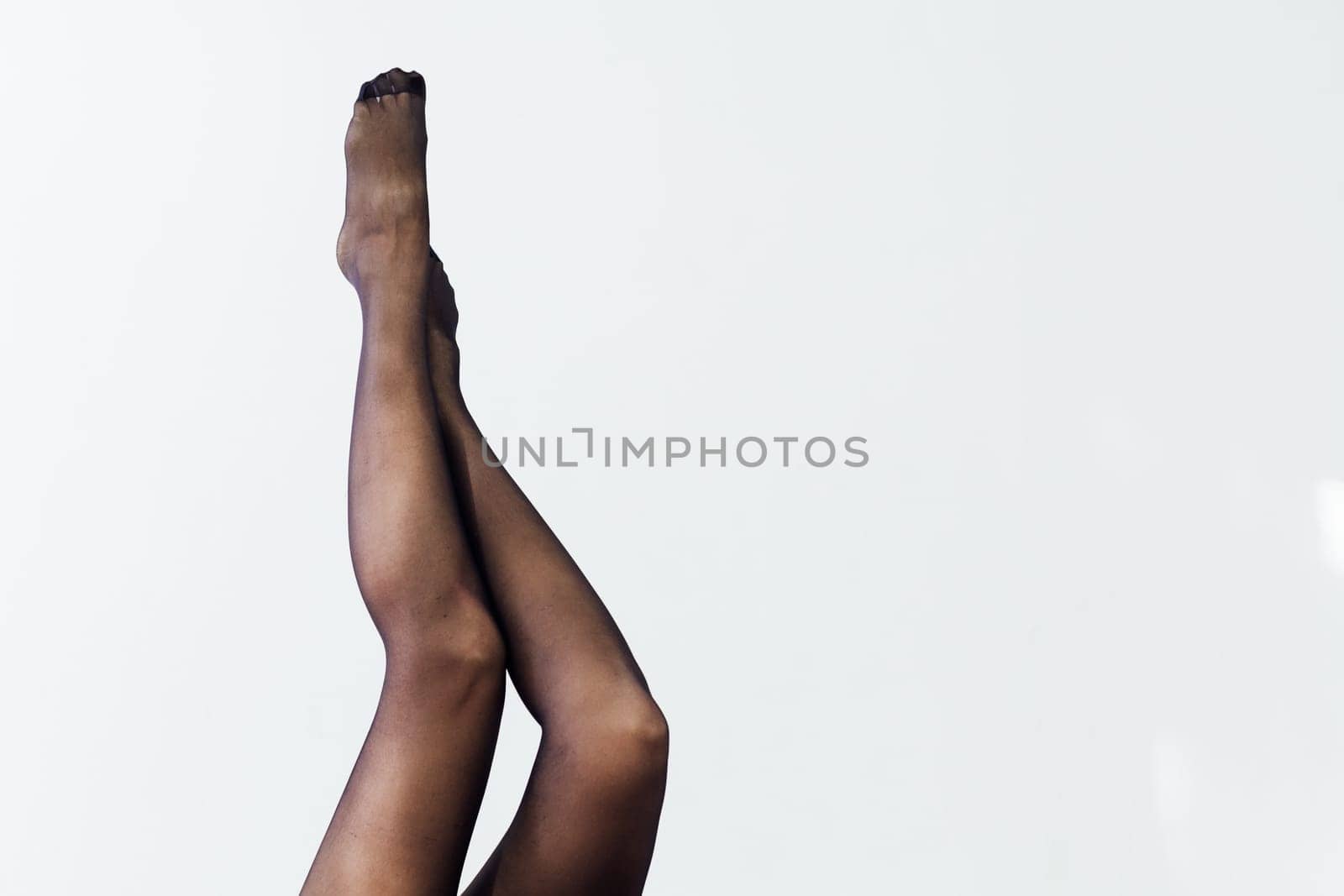 slender women's legs in black tights on a white background