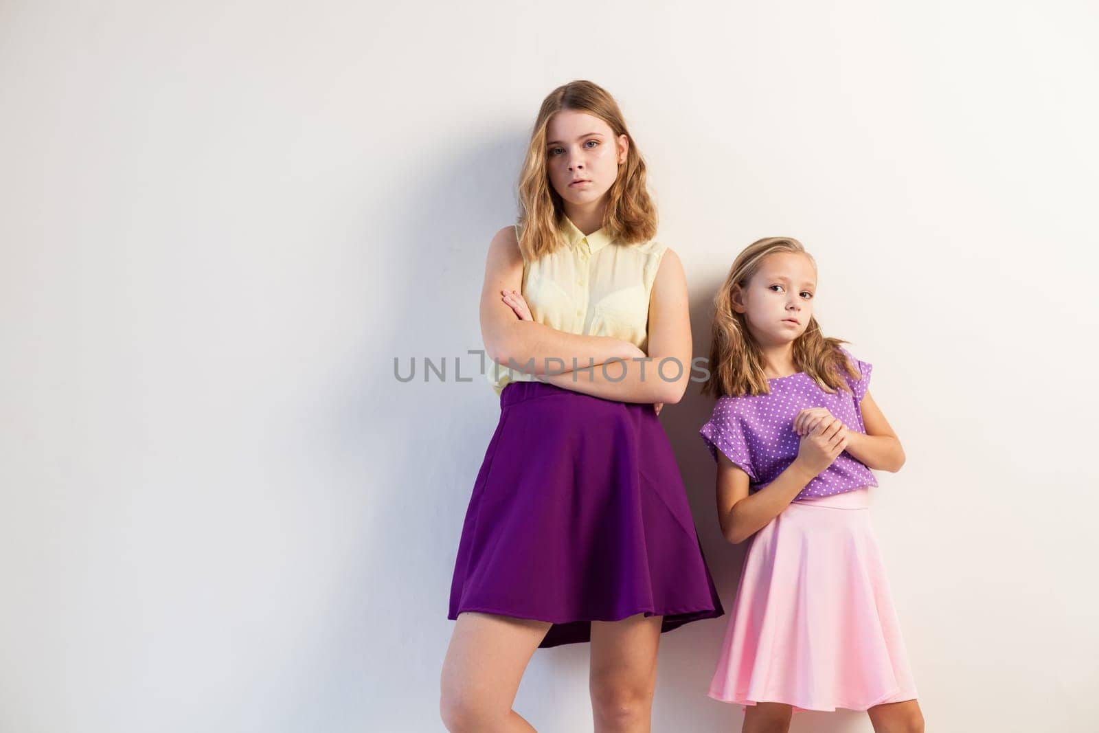 two sisters girls in colored dresses white walls 1