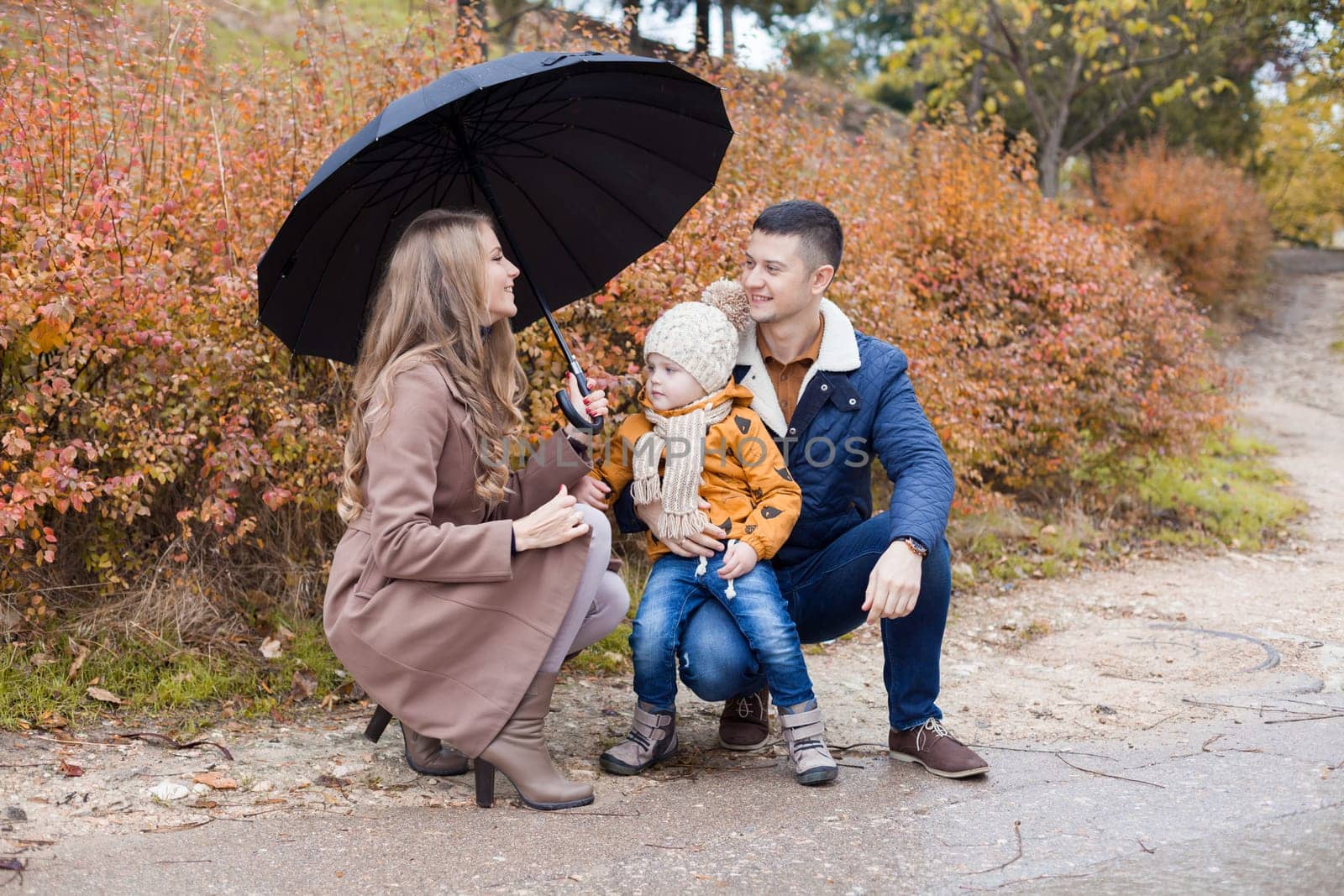 family autumn in the Park in the rain umbrella by Simakov