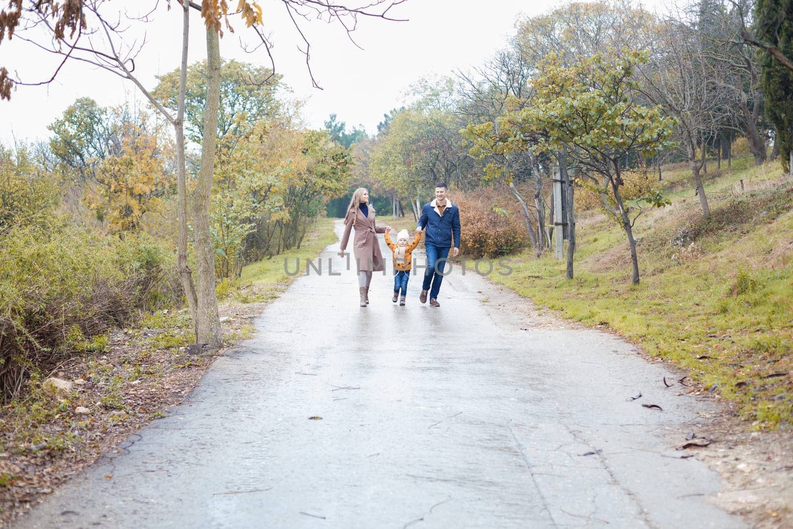 a family with a son go on road in the rain by Simakov