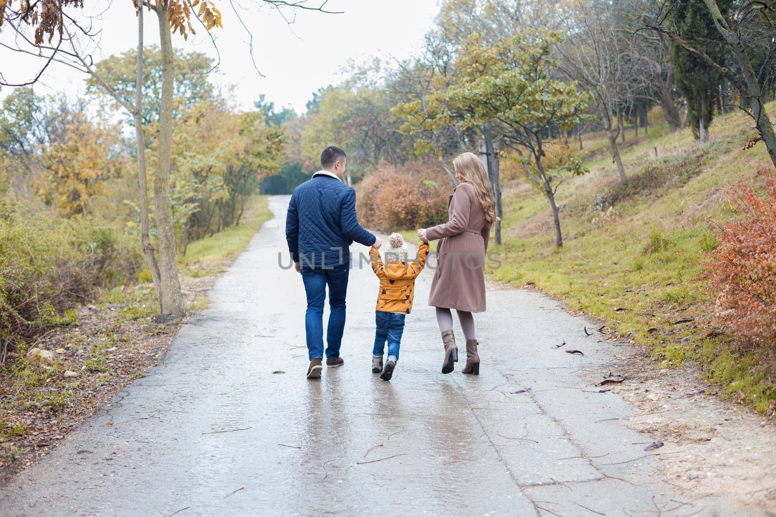 a family with a son go on road in the rain by Simakov