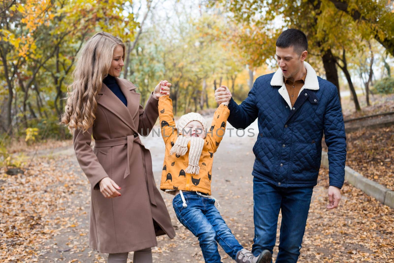 a family with a young son walk in the Park in autumn by Simakov