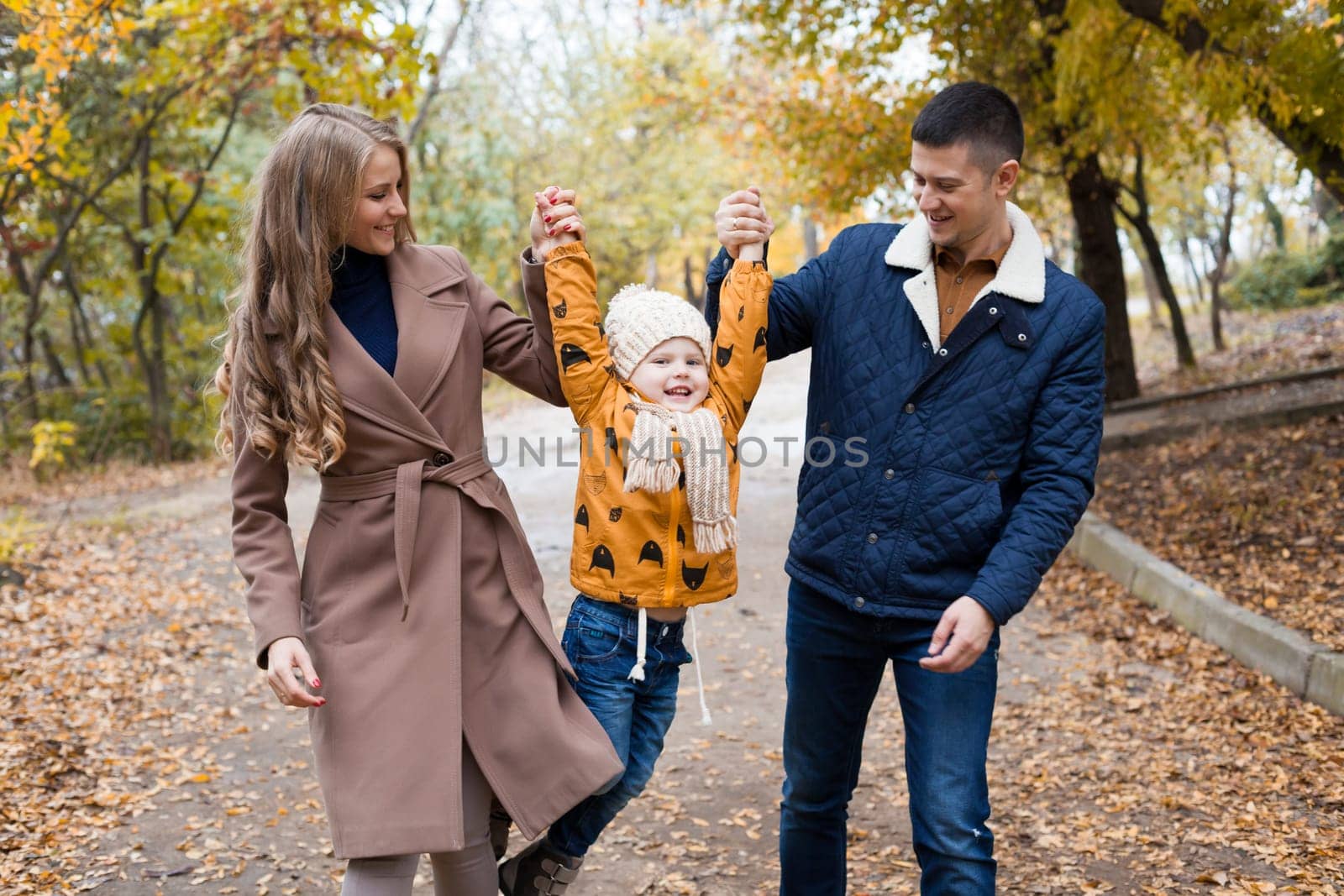 a family with a young son walk in the Park in autumn by Simakov