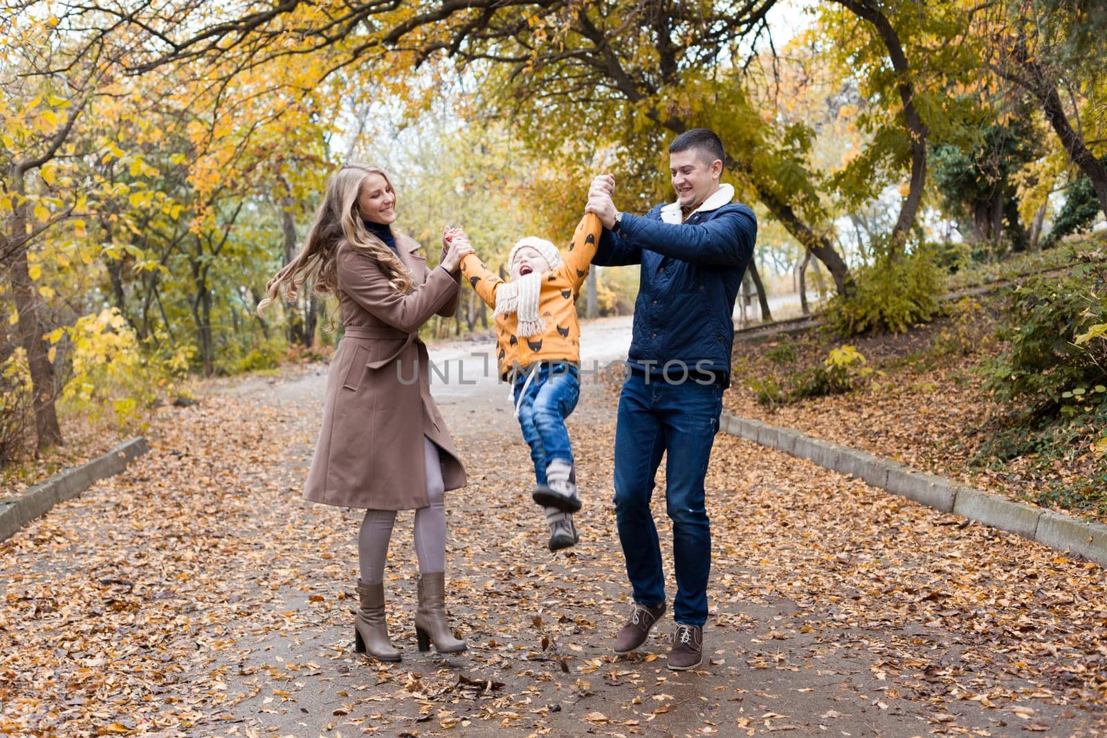 a family with a young son walk in the Park in autumn by Simakov