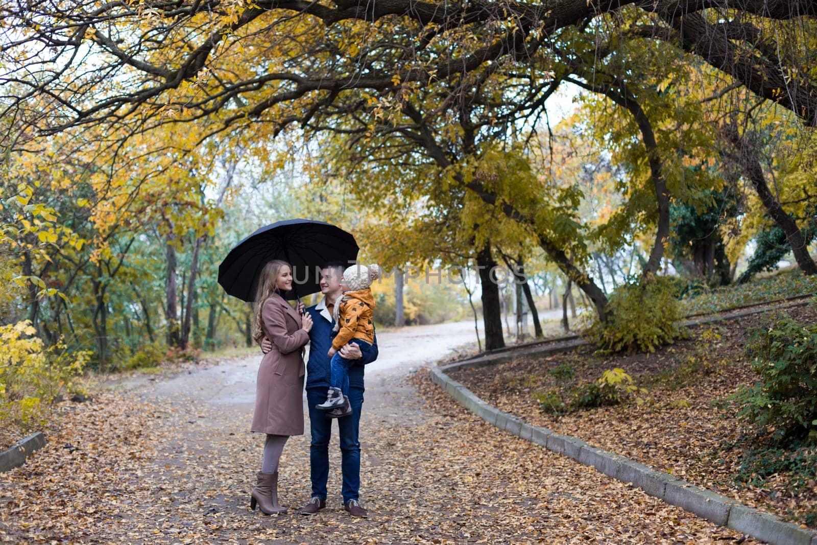 family in autumn in forest rain umbrella by Simakov