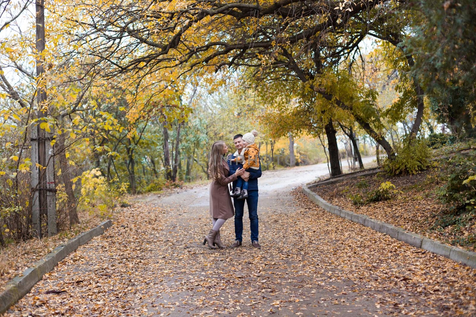 a family with a young son walk in the Park in autumn 1